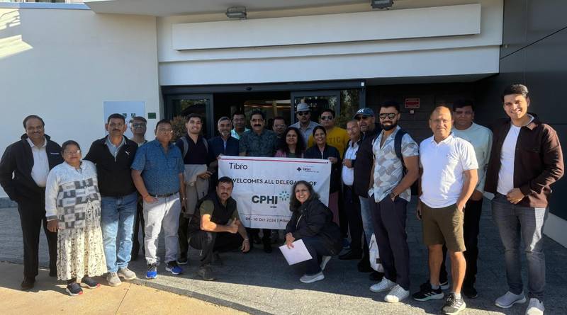 Group posing outside a building holding a CPHI event banner.