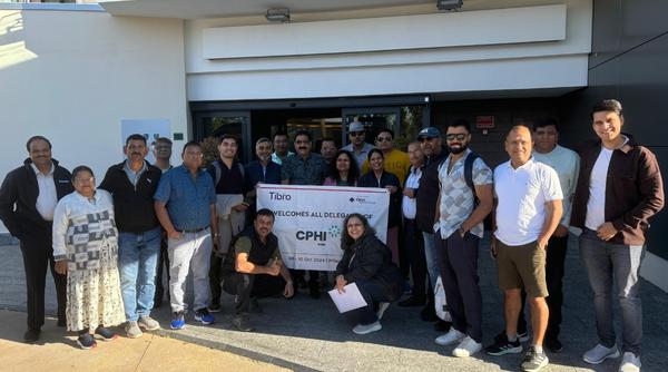 Group posing outside a building holding a CPHI event banner.