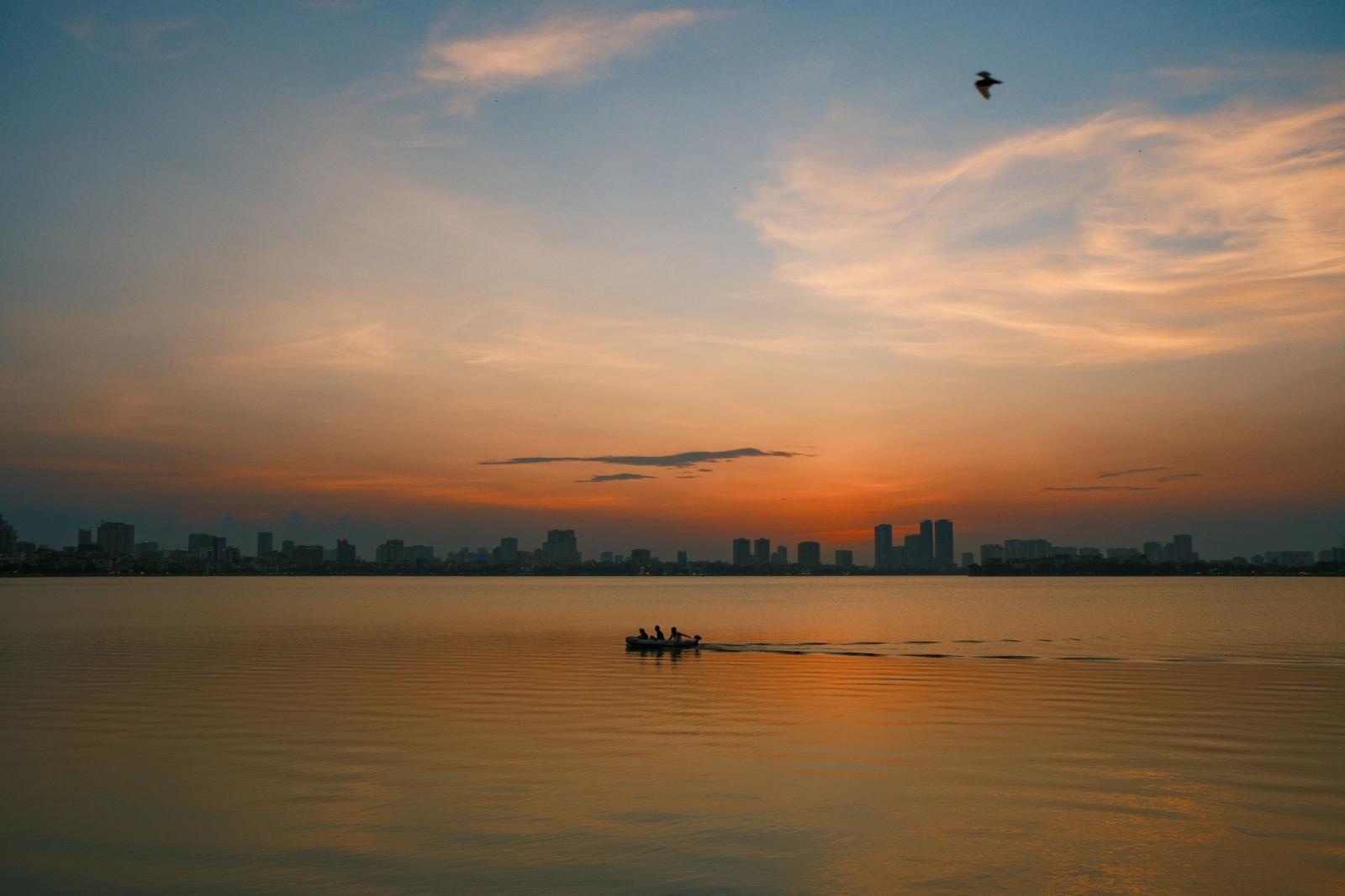 A tranquil view of a boat on West Lake, Hanoi, at sunset. Perfect for travel inspiration
