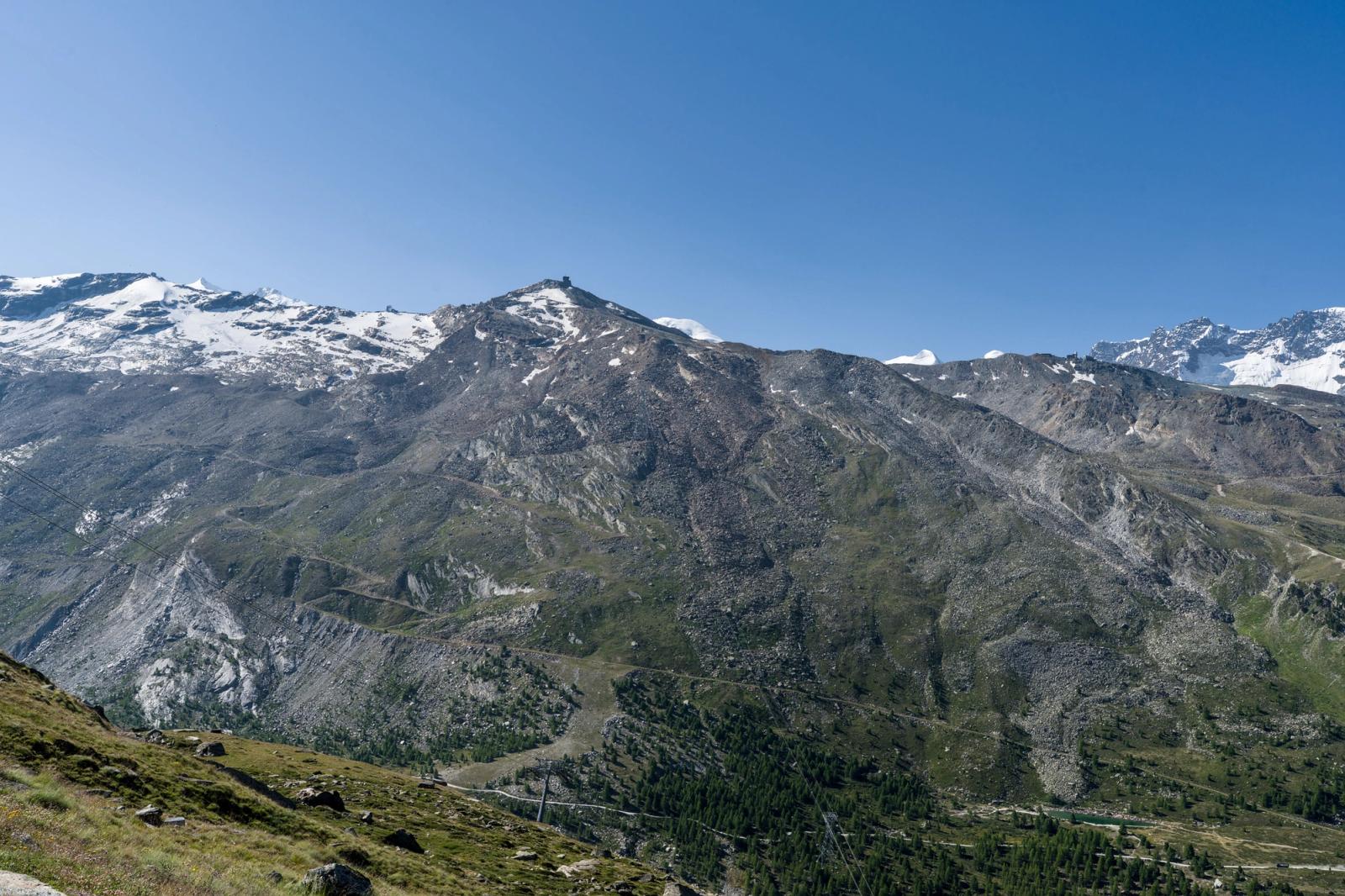 Mountain valley with a switchback road threading between snow-streaked ridges