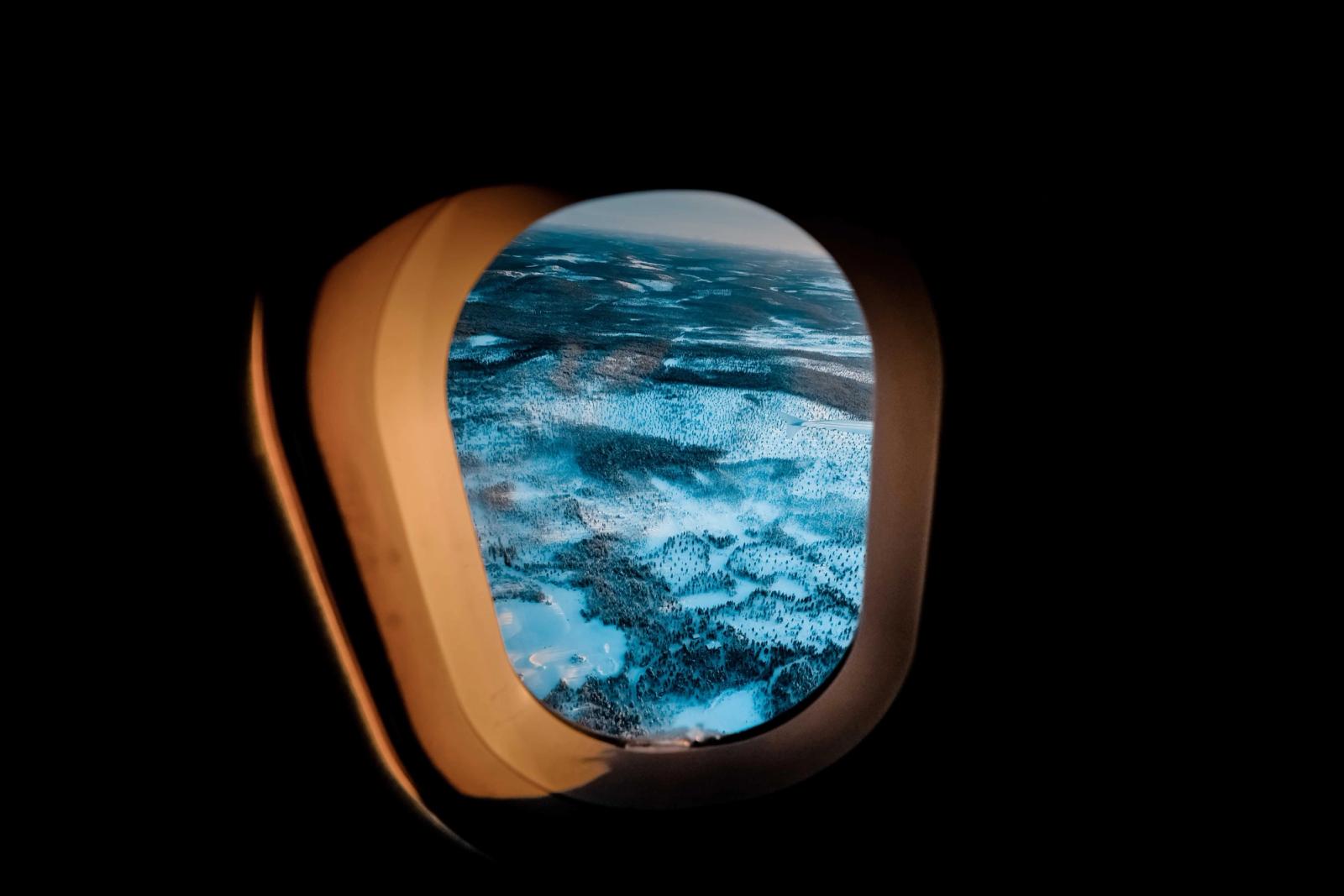 Aerial view of a snowy Finnish landscape through an airplane window, capturing winter's beauty
