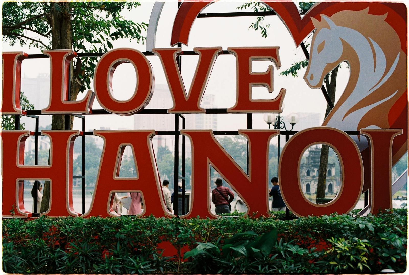 A large red I Love Hanoi sign with a horse emblem in a park