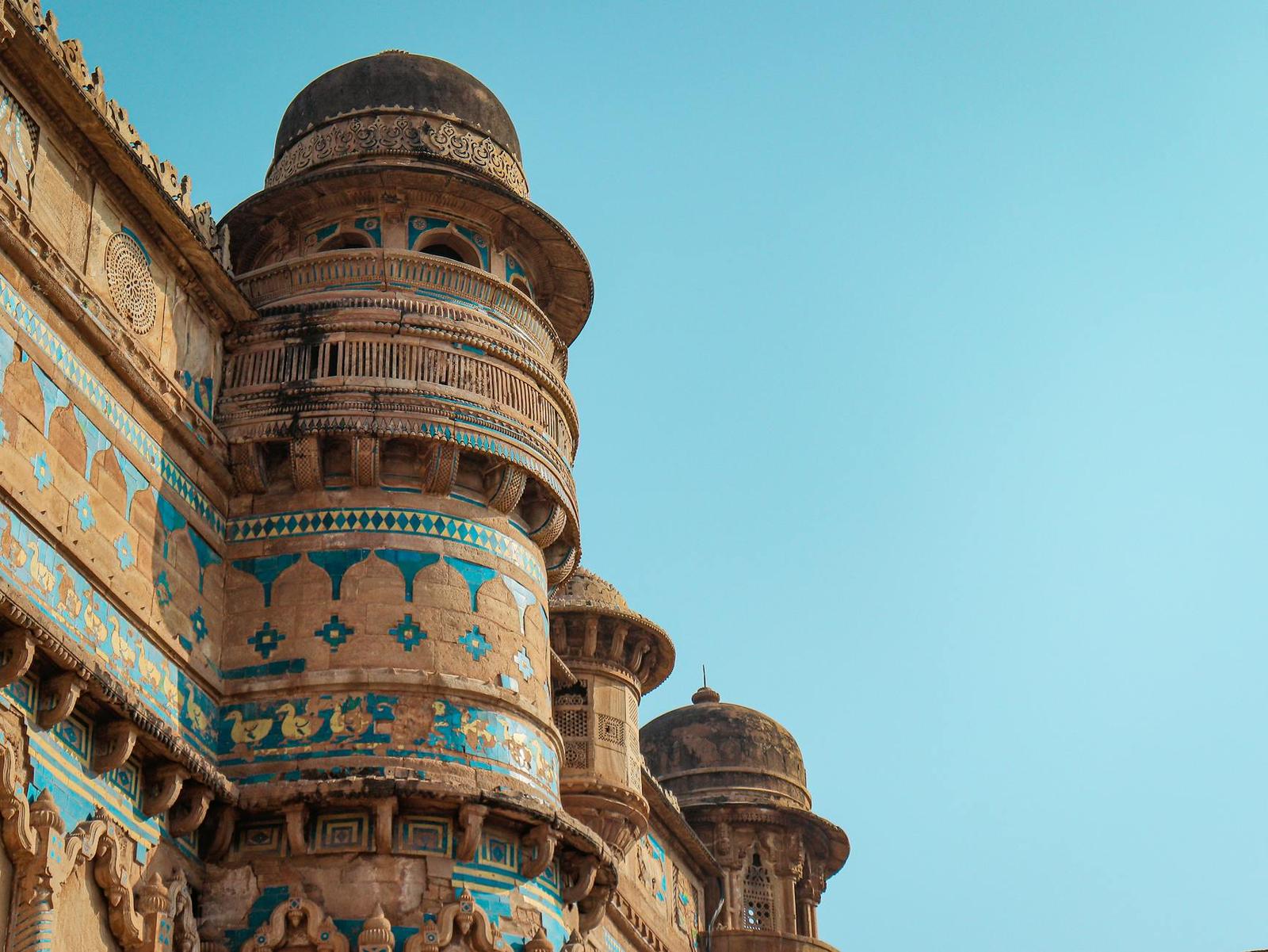 Domed sandstone turrets banded with turquoise tilework against a clear sky