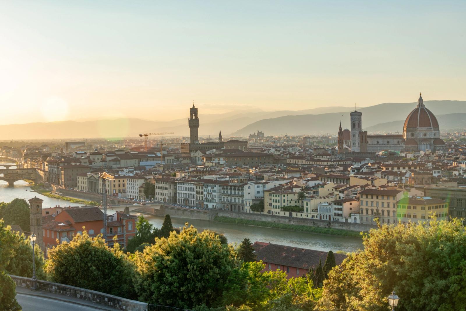 A stunning panoramic view of Florence, Italy, at sunrise featuring the iconic Duomo and Arno River