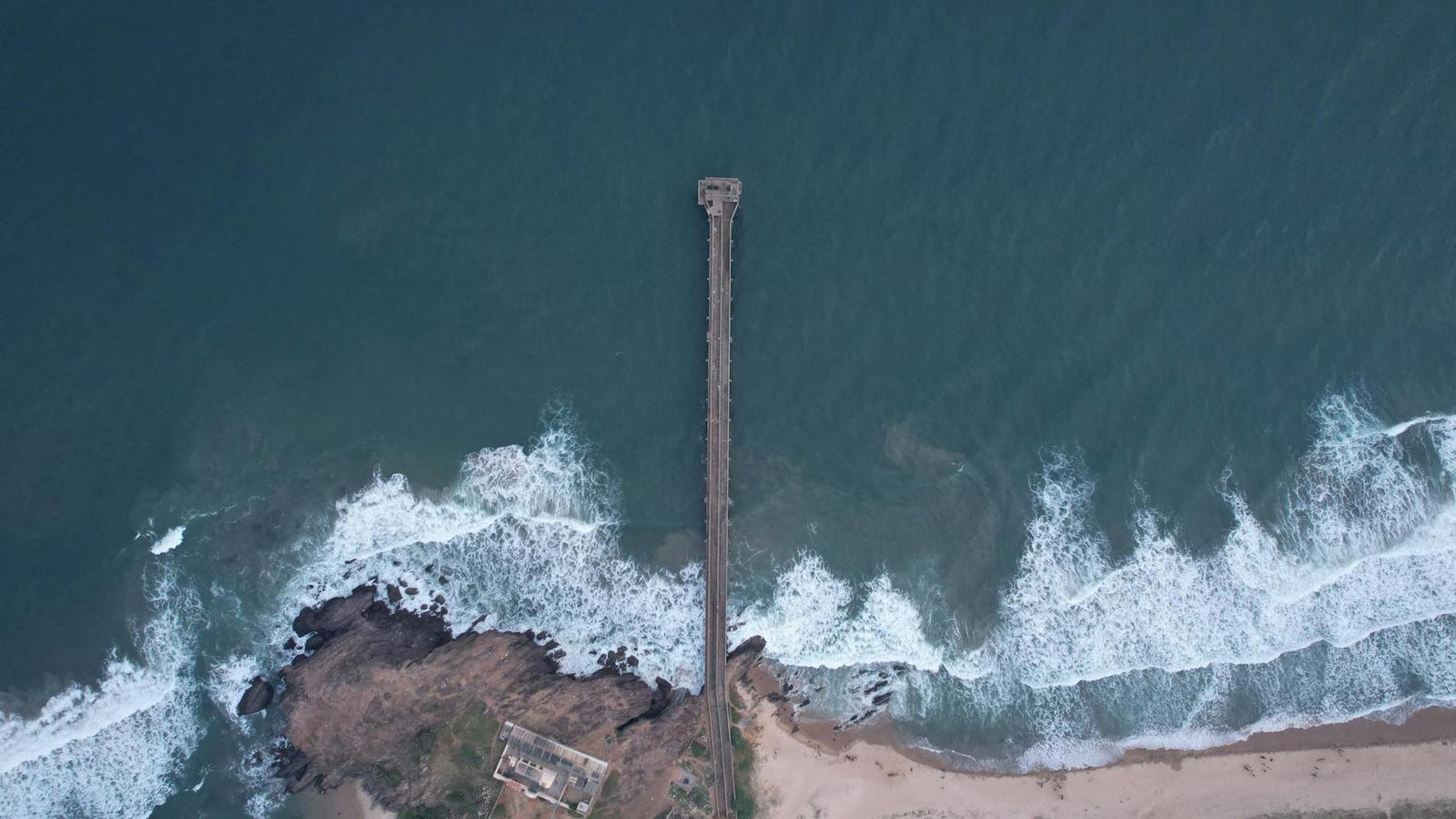 An aerial view of a long pier stretching into the sea