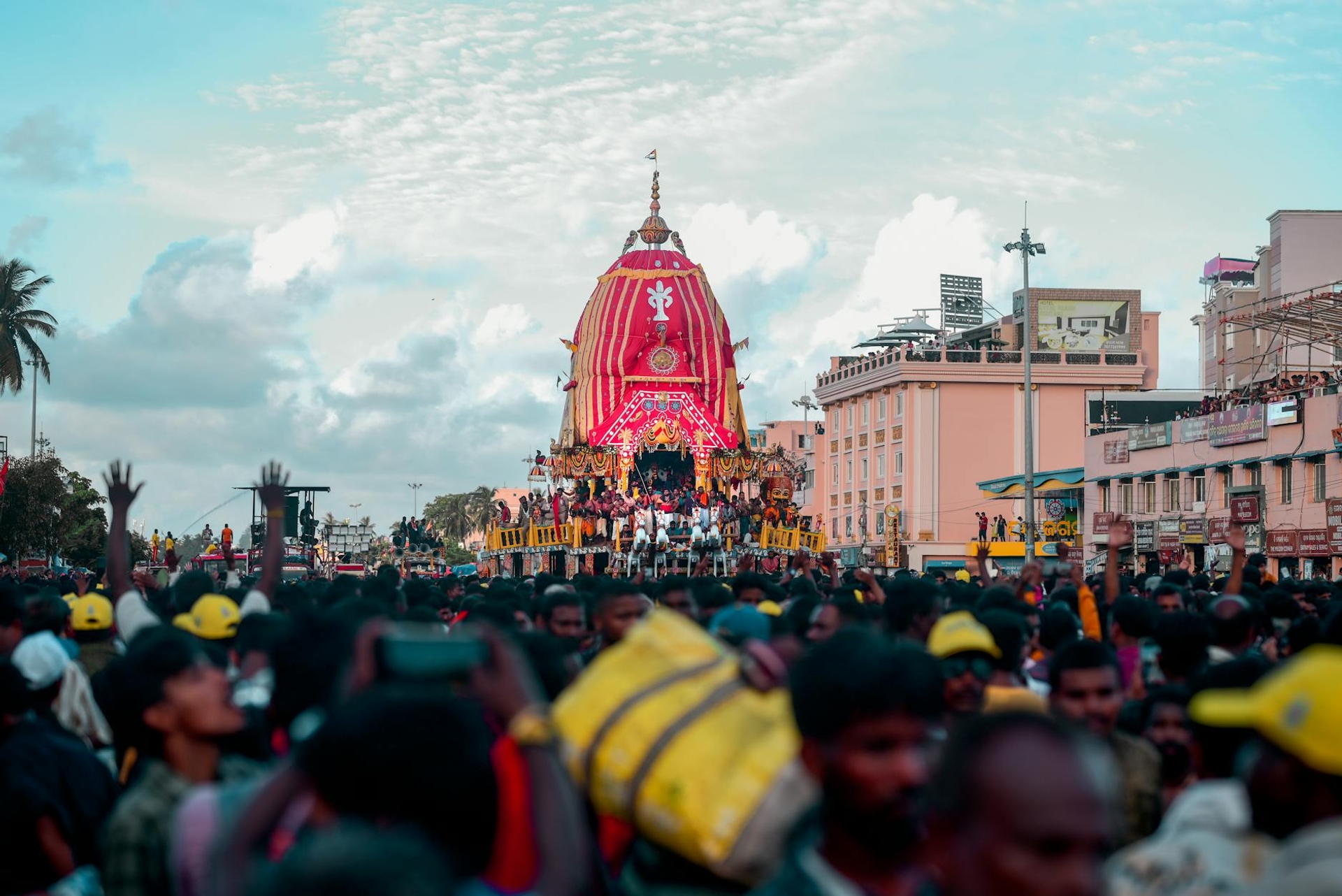 Dense crowd gathered before an ornately decorated festival chariot
