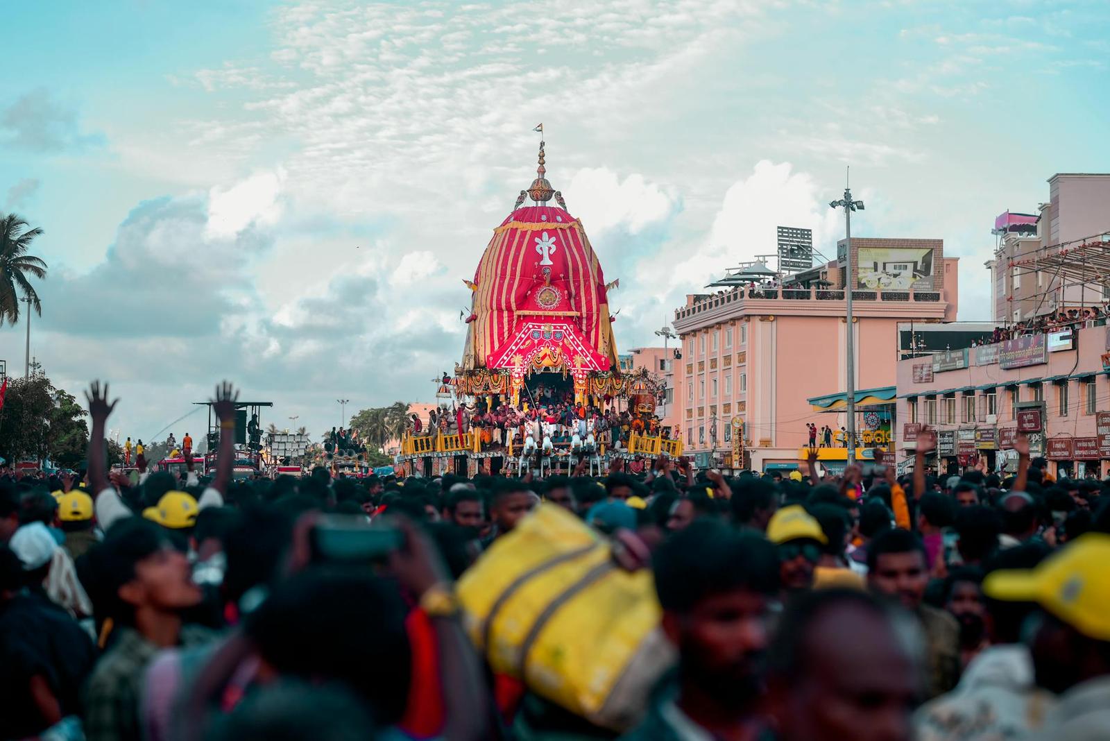 Dense crowd gathered before an ornately decorated festival chariot