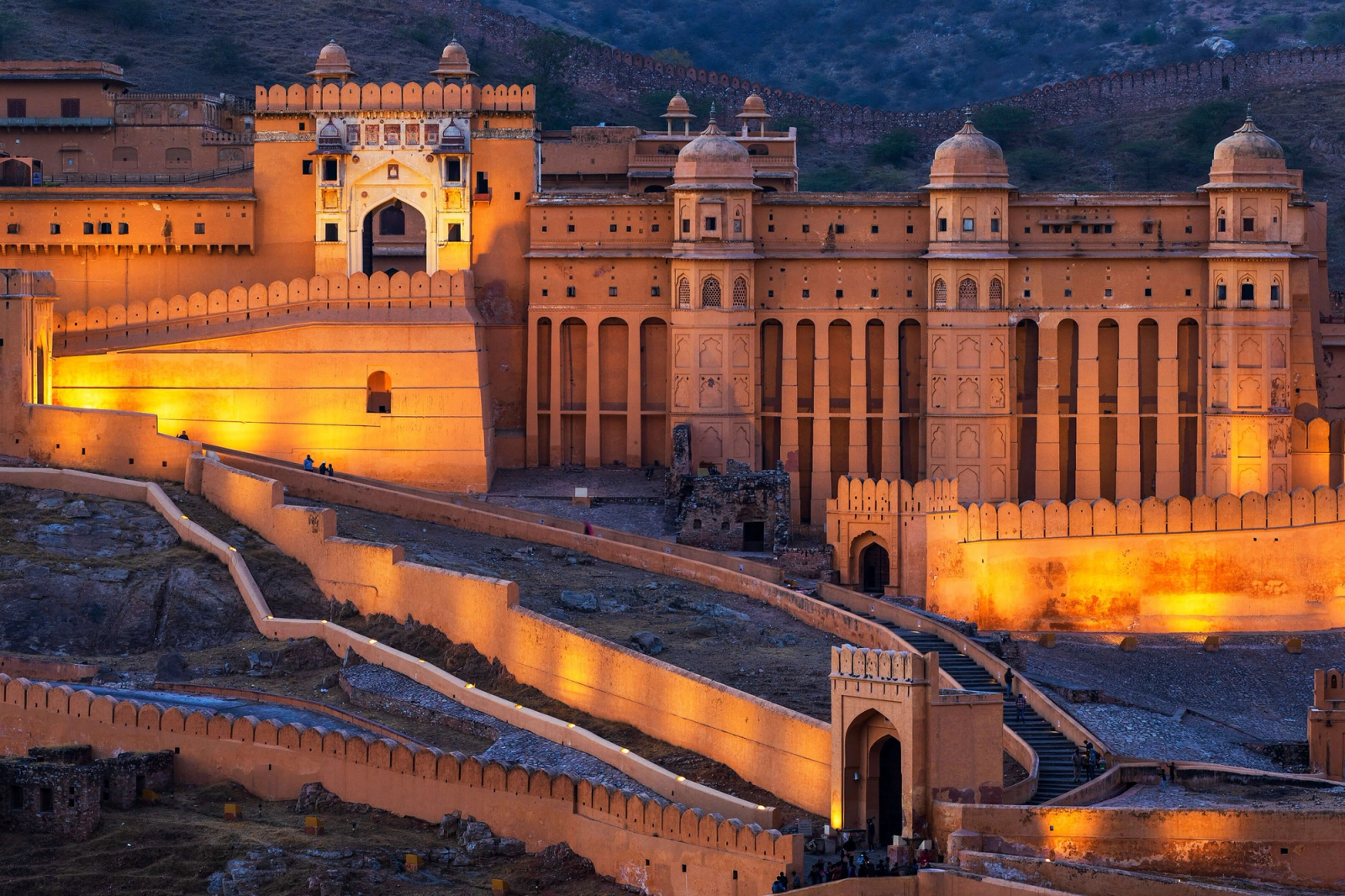 A hilltop fort illuminated gold against the blue hour sky