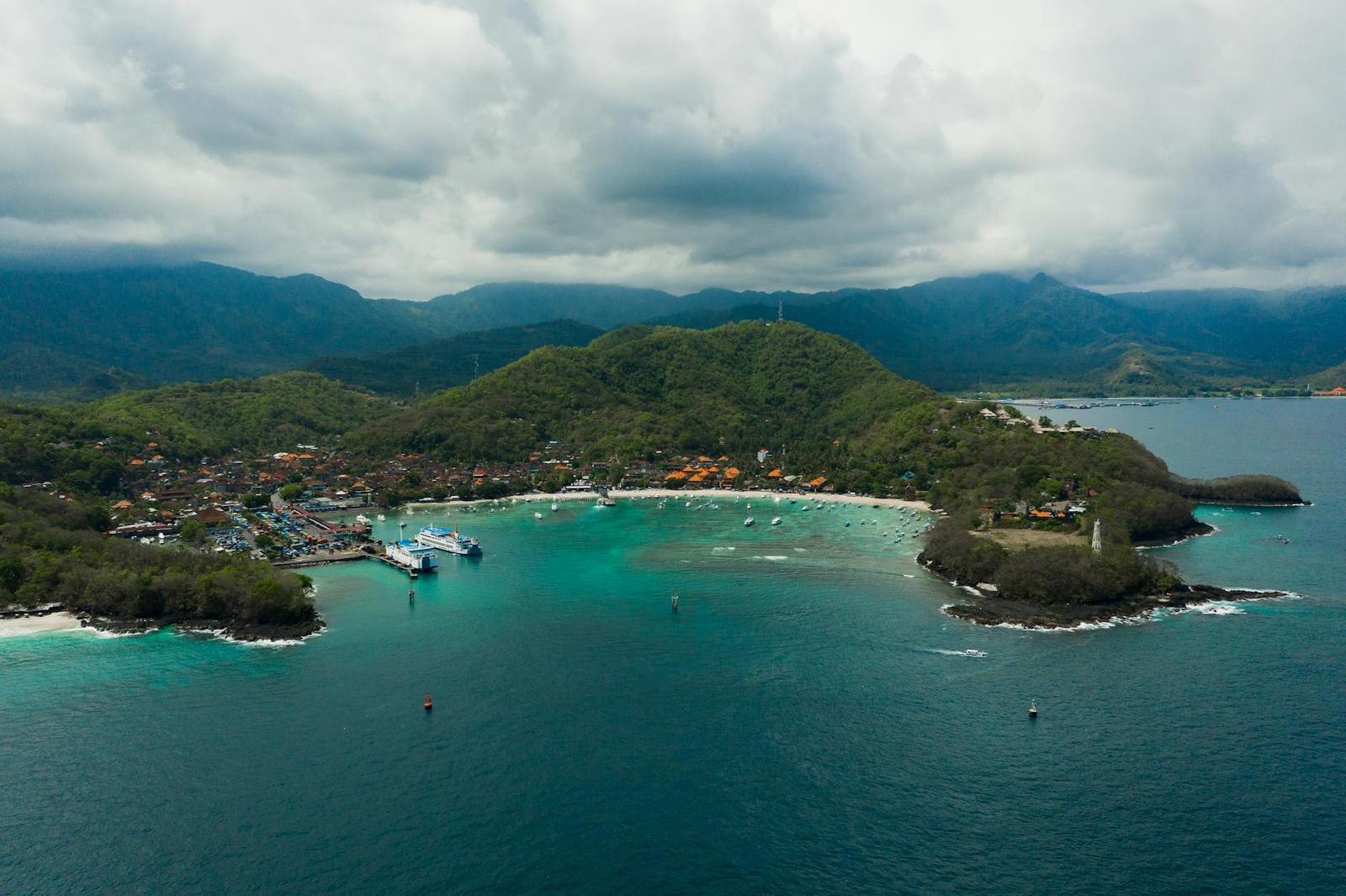 An aerial view of a turquoise bay framed by a forested headland