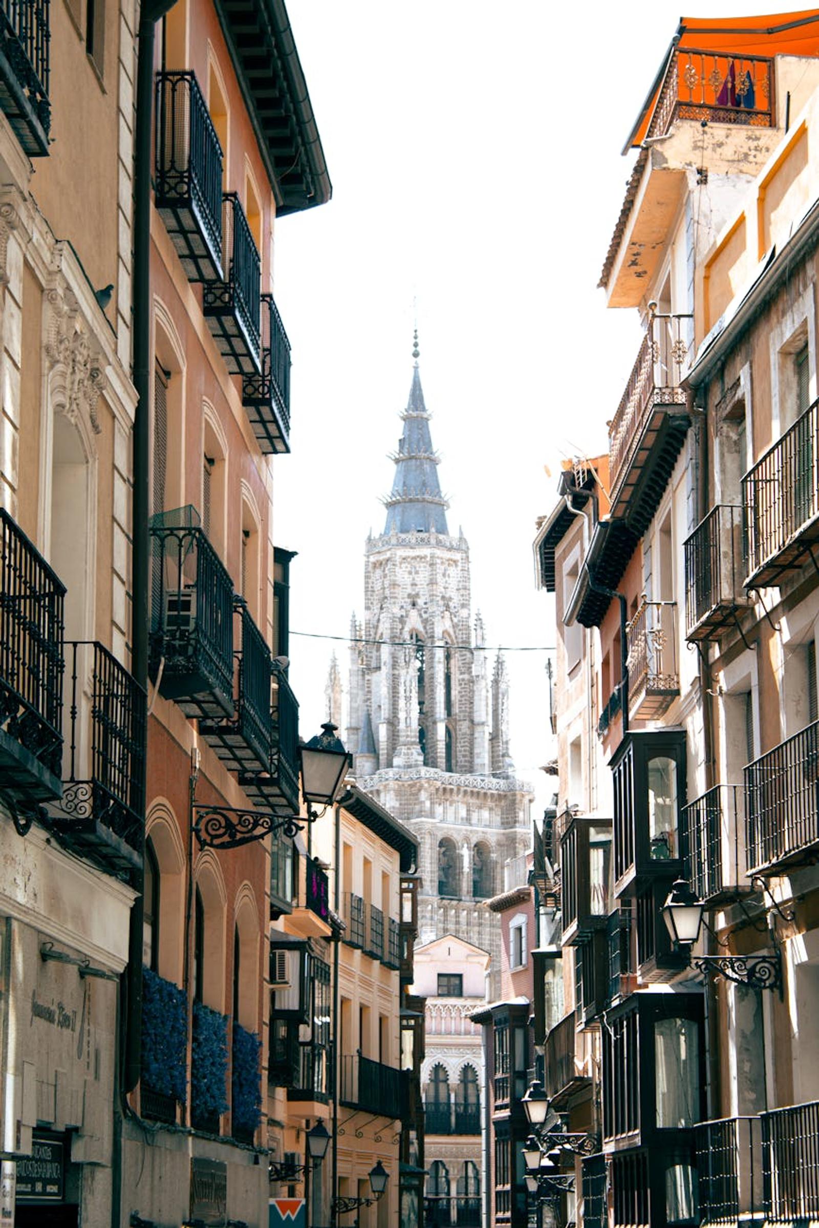 A beautiful perspective of the Toledo Cathedral tower framed by historic urban streets in Spain