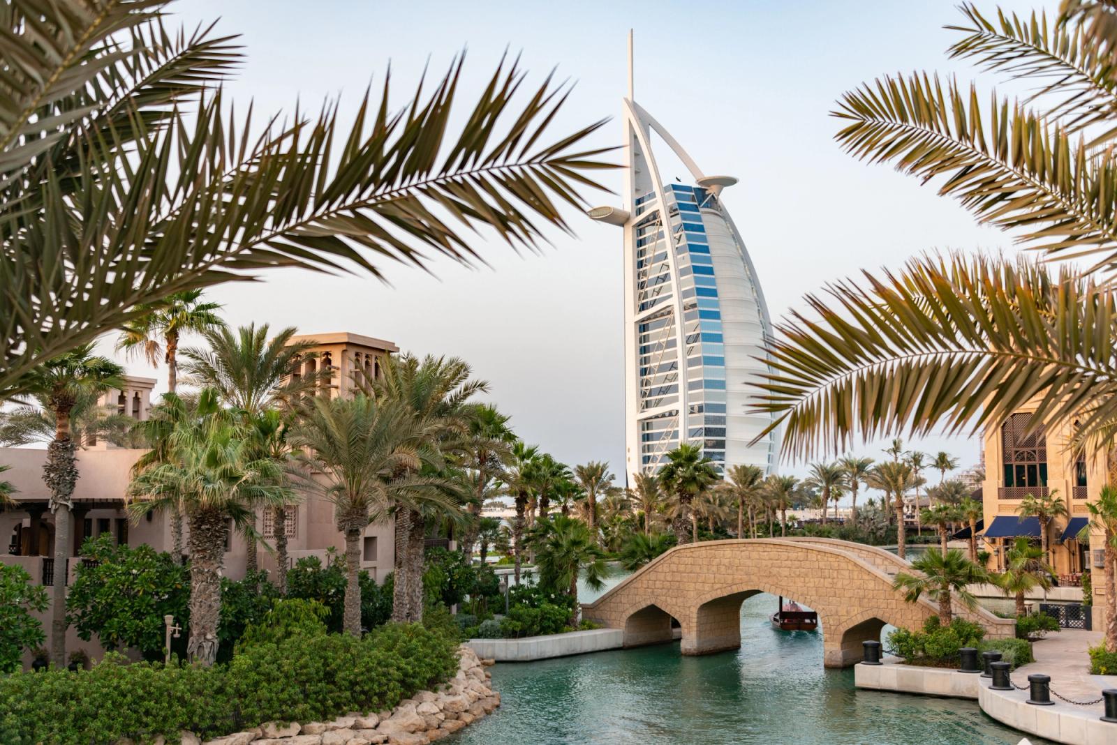 Sail-shaped Burj Al Arab hotel framed by palm trees and a footbridge