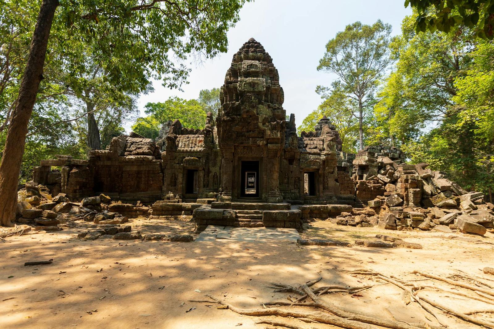 Crumbling stone temple towers surrounded by dense forest and rubble