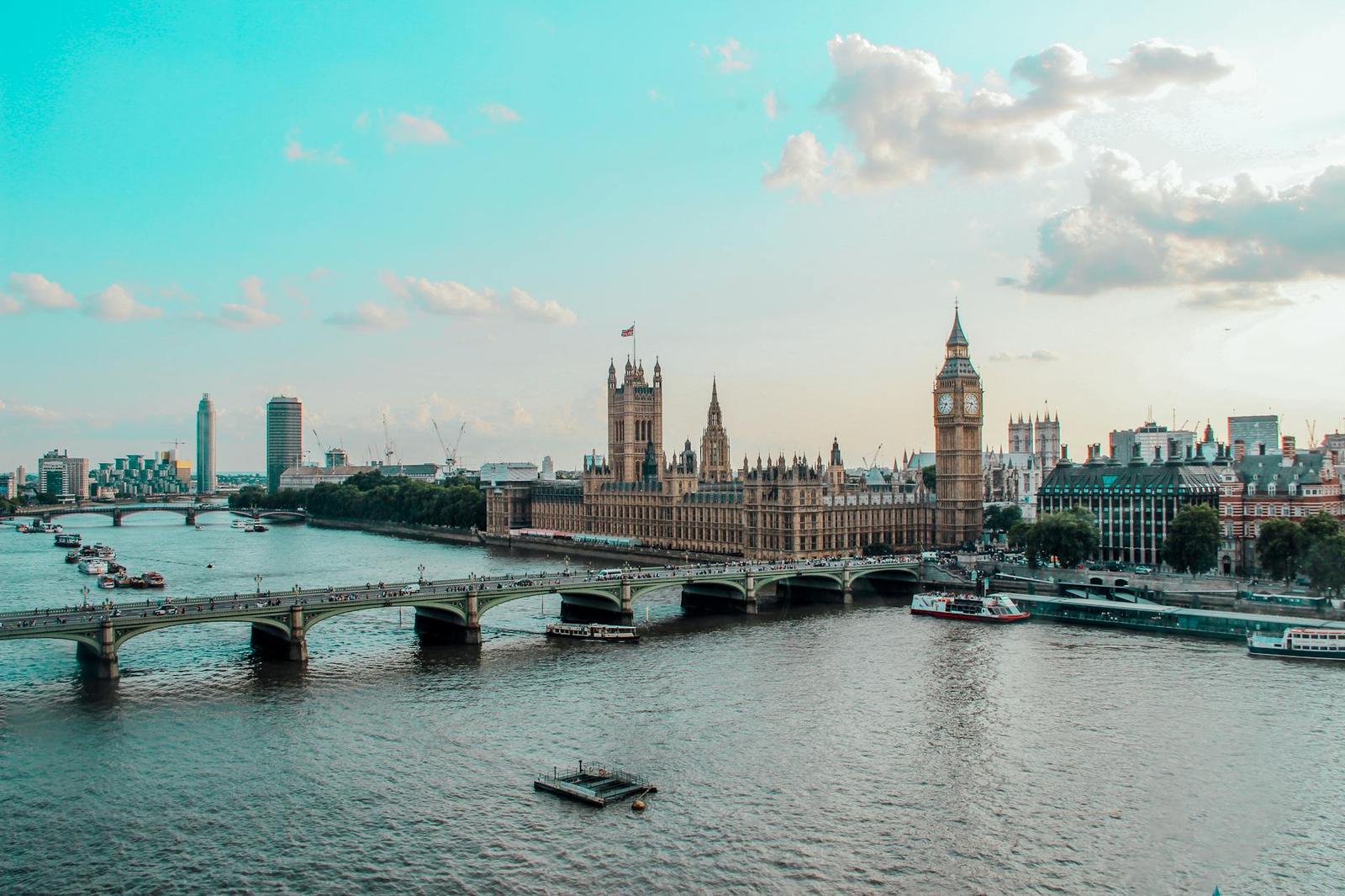A river bend lined with historic parliament buildings and a clock tower under soft skies