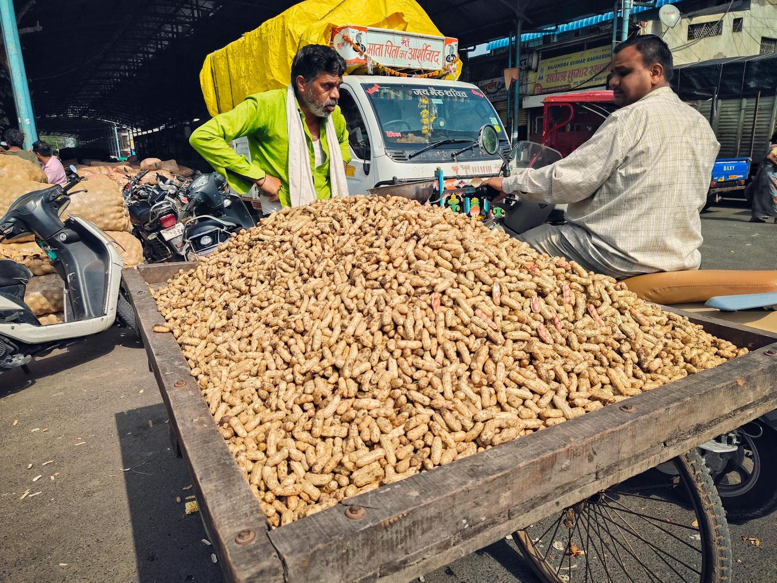 A vendor cart heaped with peanuts as two men stand beside it