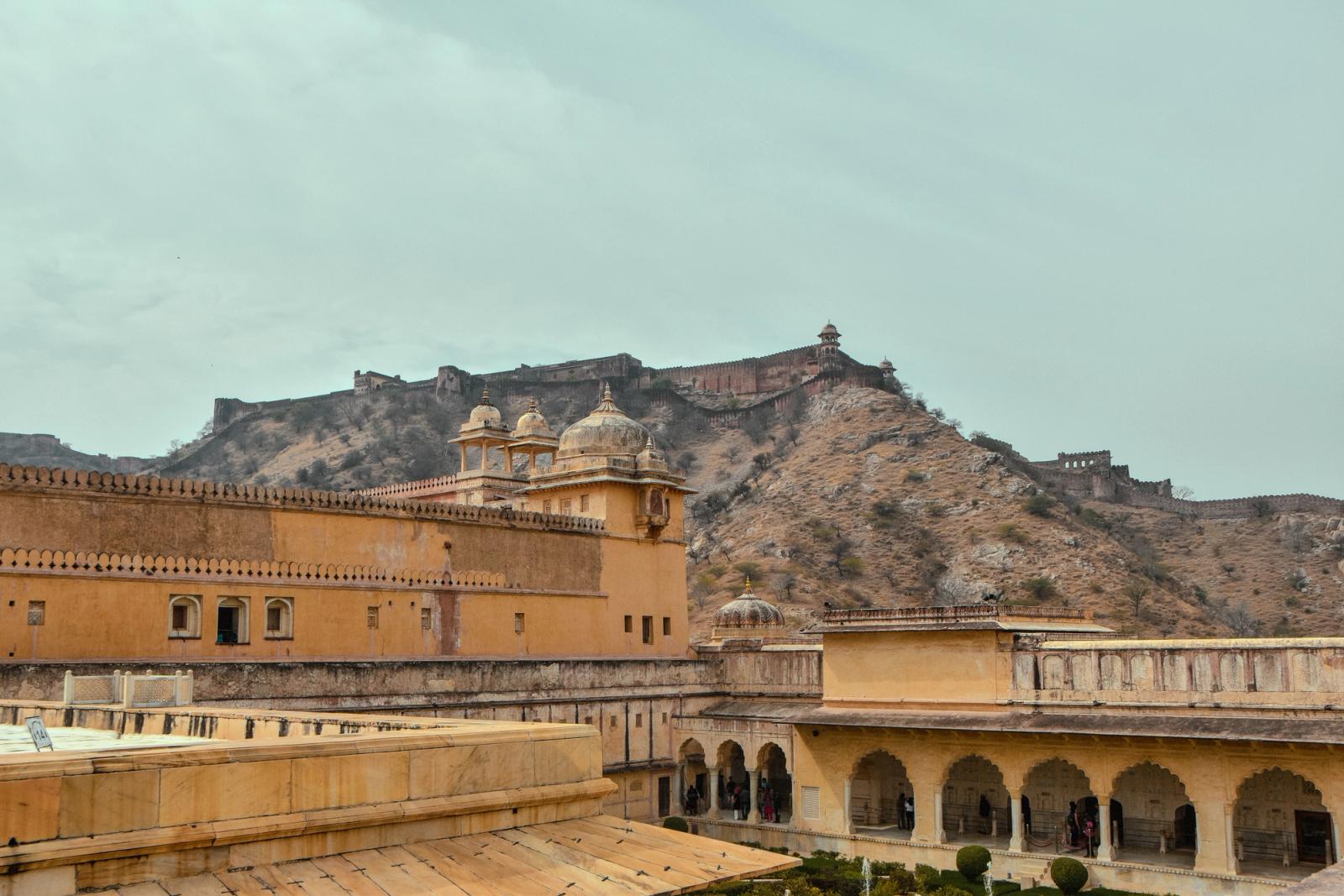 A hillside fort wall snaking above a palace courtyard