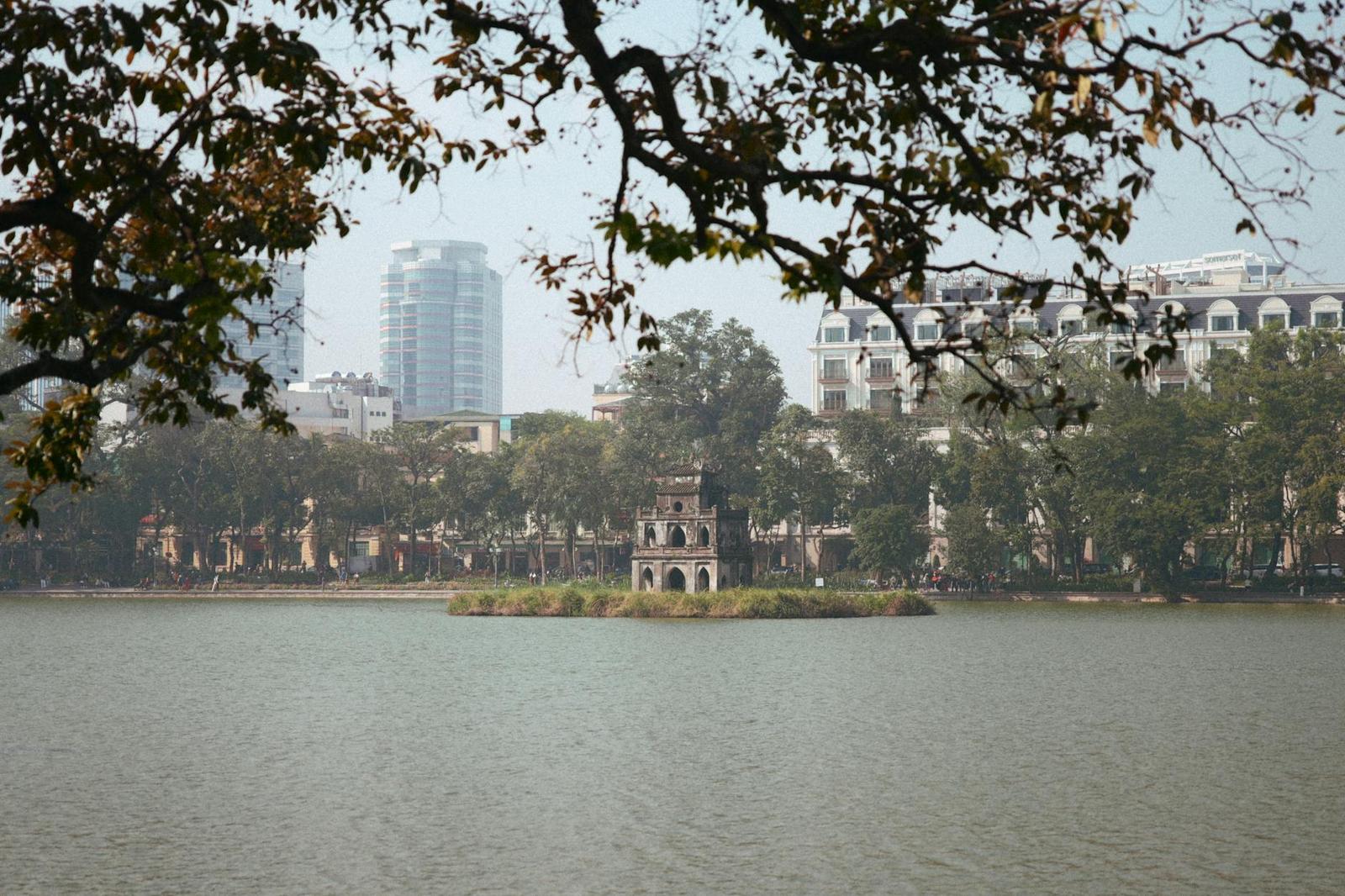 Peaceful view of Hoan Kiem Lake with Turtle Tower in Hanoi, Vietnam with city skyline
