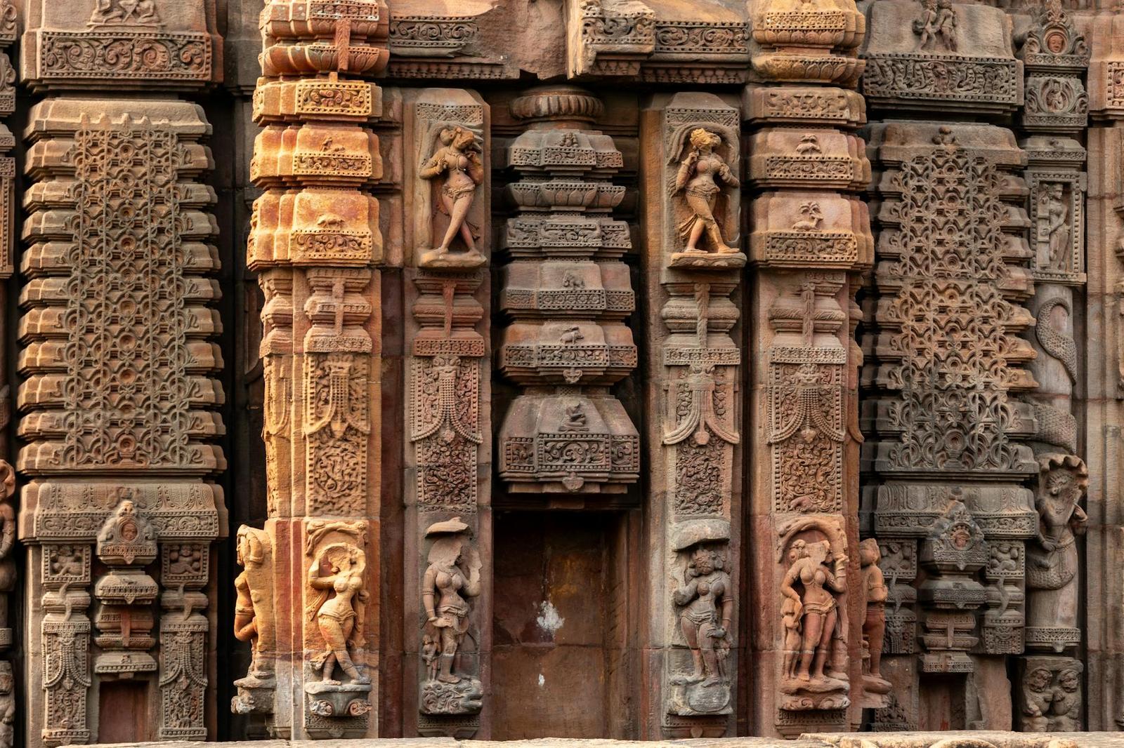 Carved stone pillars with figures and floral reliefs flanking a temple doorway