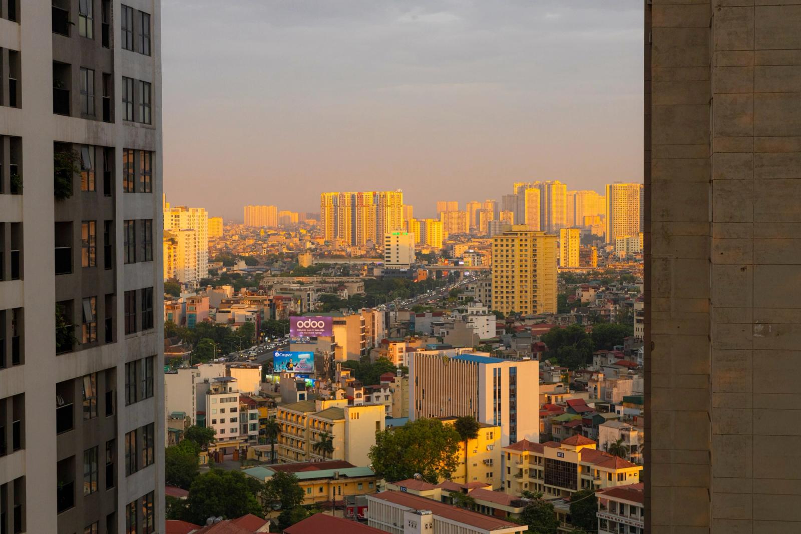 Stunning sunset over Hanoi cityscape with golden light reflecting on buildings, creating a warm urban atmosphere