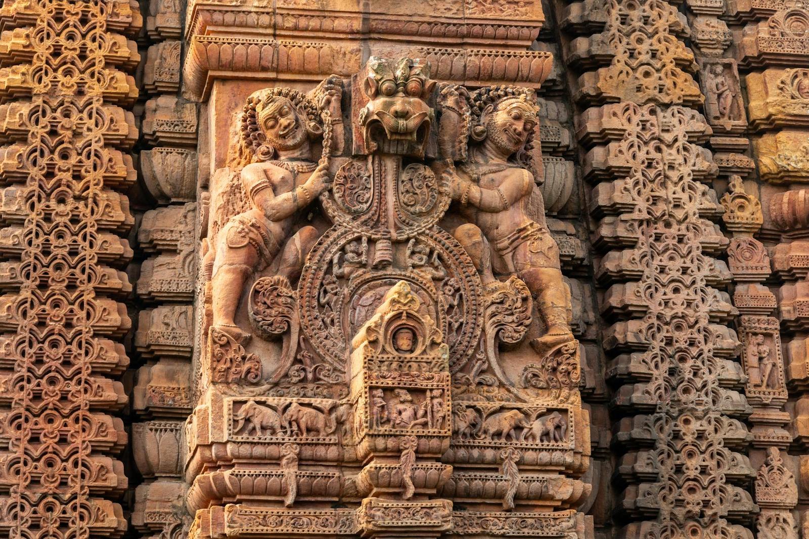 Ornate stone relief carving of deities flanking a small niche on a temple wall