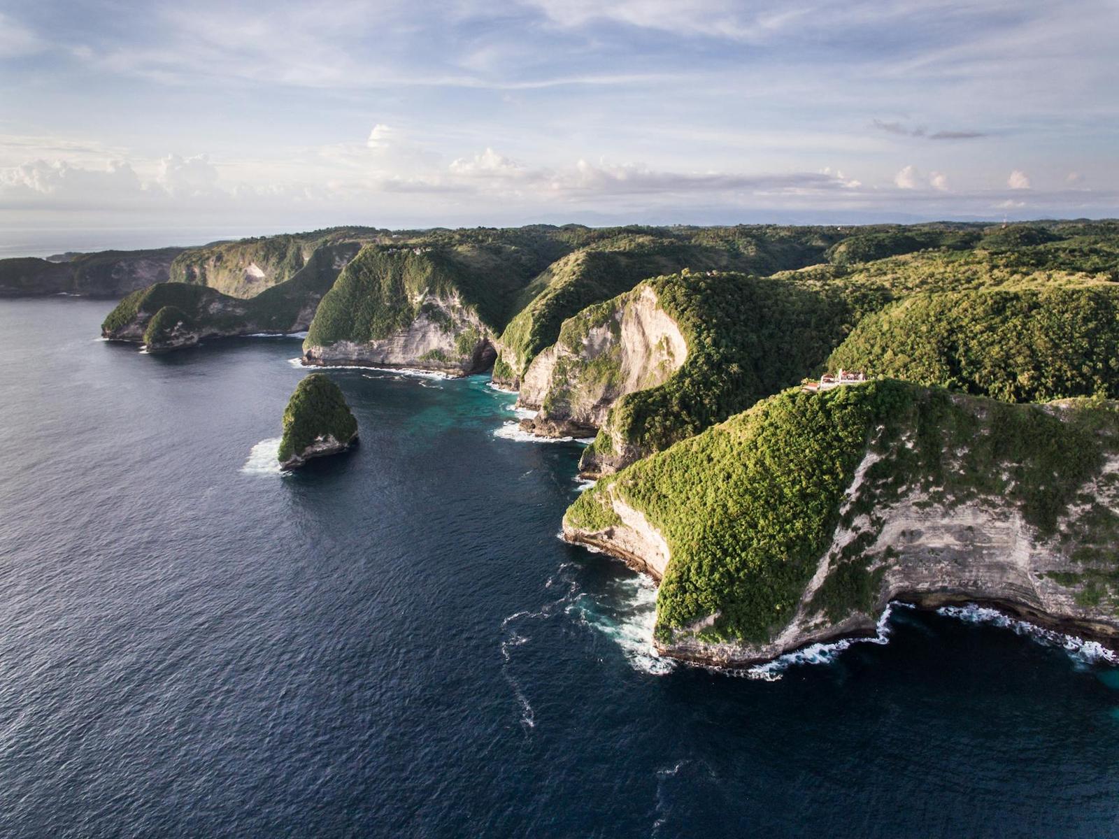 Drone shot of lush green cliffs and turquoise ocean at Nusa Penida in Bali, Indonesia