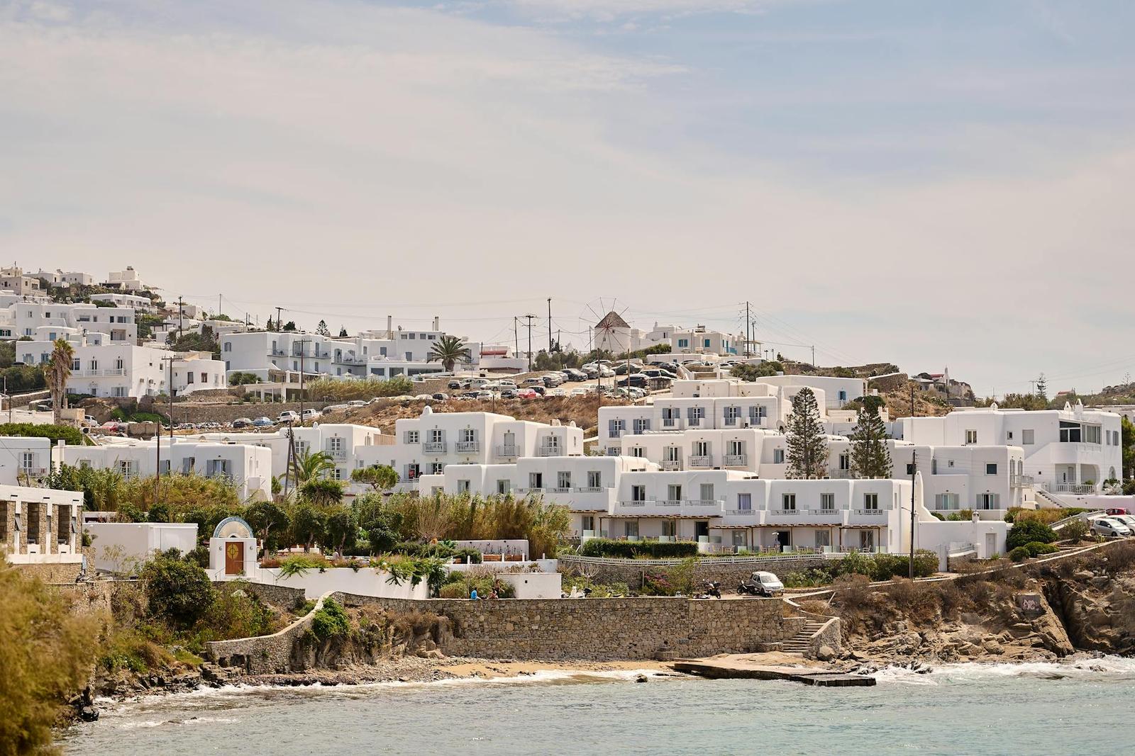White cubic buildings on a hillside above a rocky coastline
