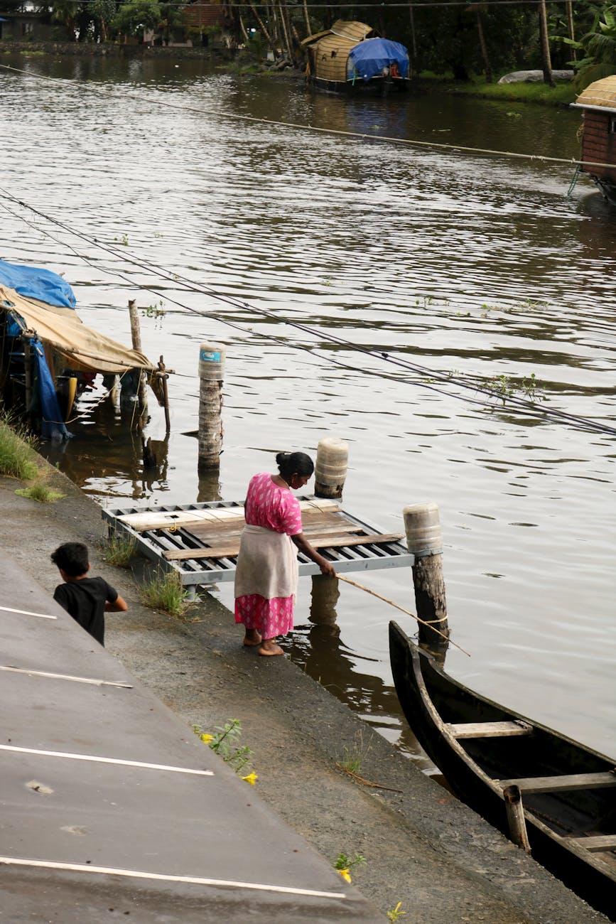 A woman stands near a dock on the Alappuzha backwaters in Kerala, India