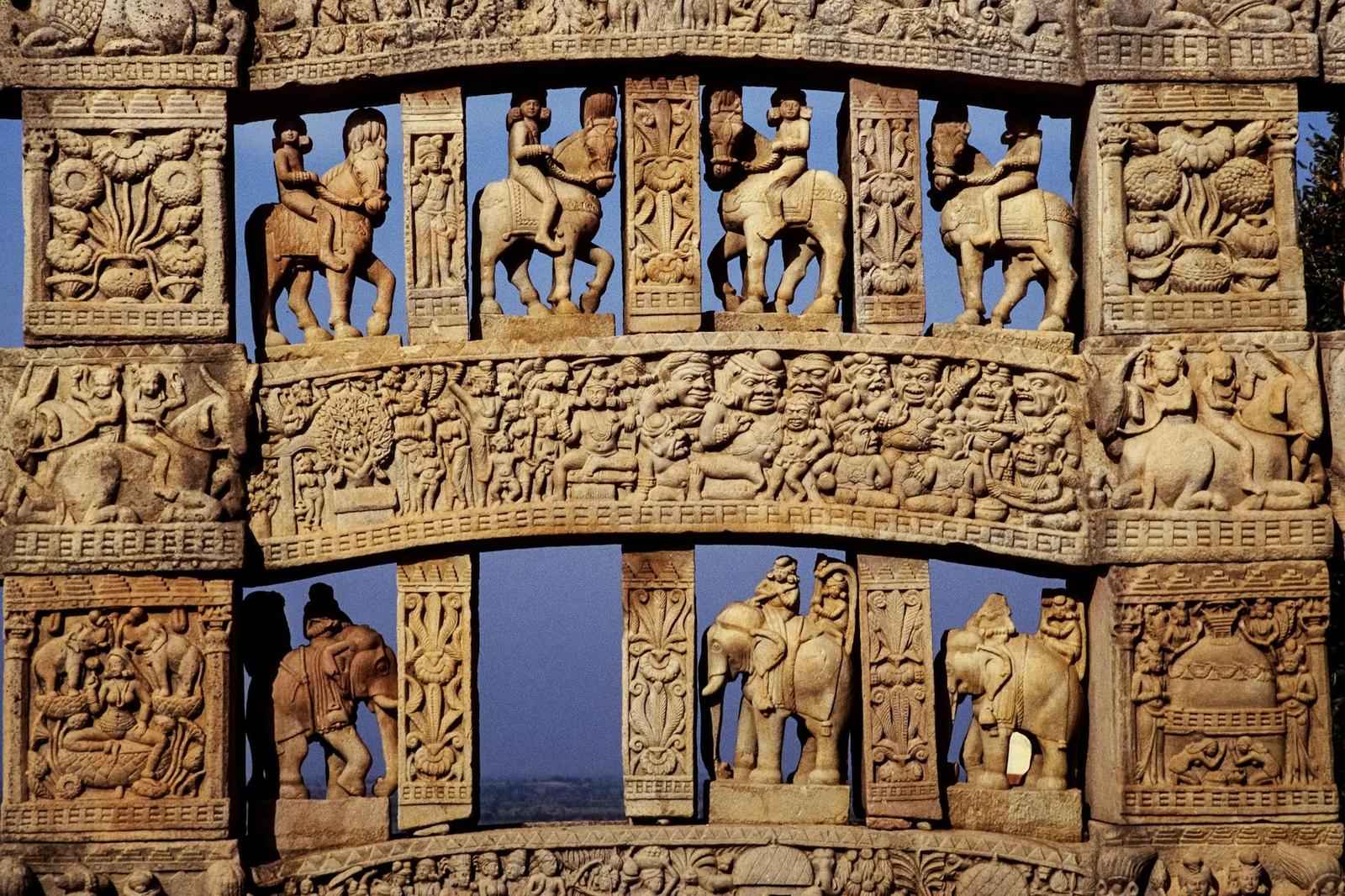 Close-up of an ancient stone gateway carved with riders on horses and elephants