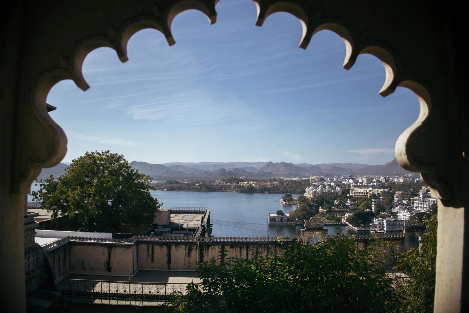 Breathtaking view of Udaipur city through a decorative archway, showcasing Lake Pichola and surrounding architecture