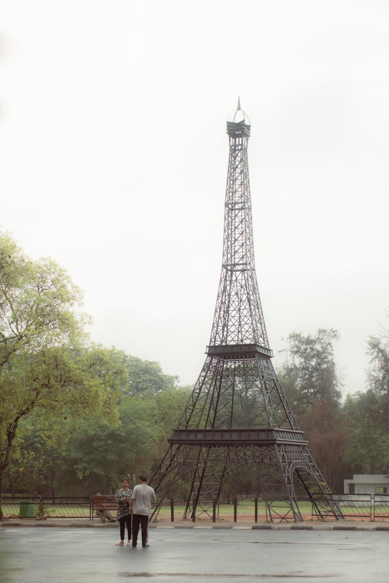 Replica of Eiffel Tower in Chandigarh park with trees and two people nearby