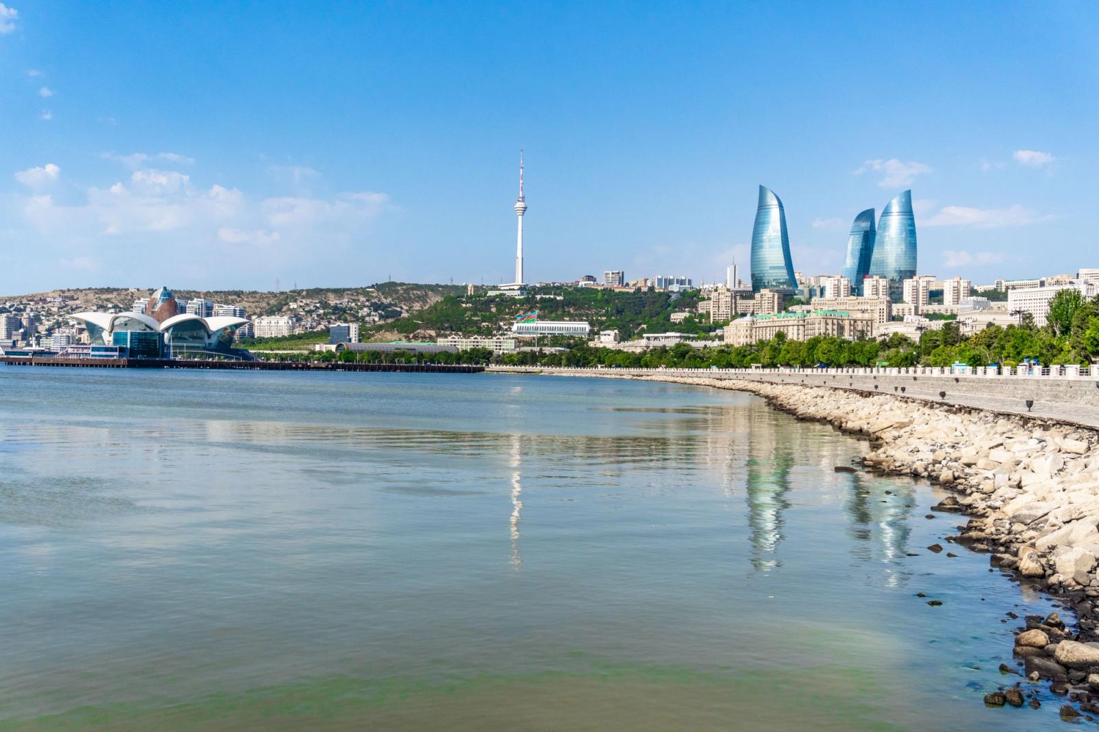 A stunning view of Baku's skyline featuring the iconic Flame Towers and the Caspian Sea on a sunny day