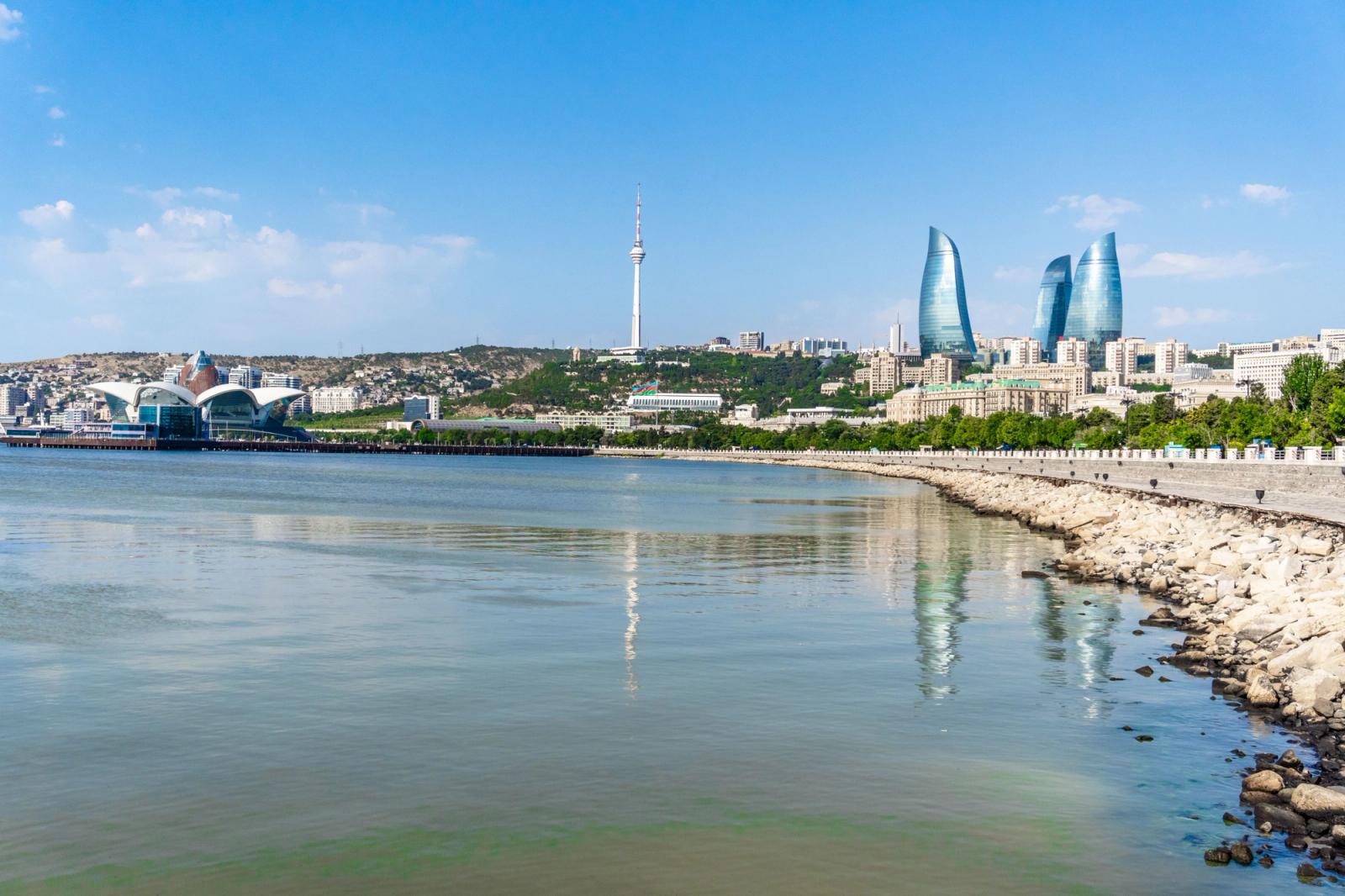 A stunning view of Baku's skyline featuring the iconic Flame Towers and the Caspian Sea on a sunny day