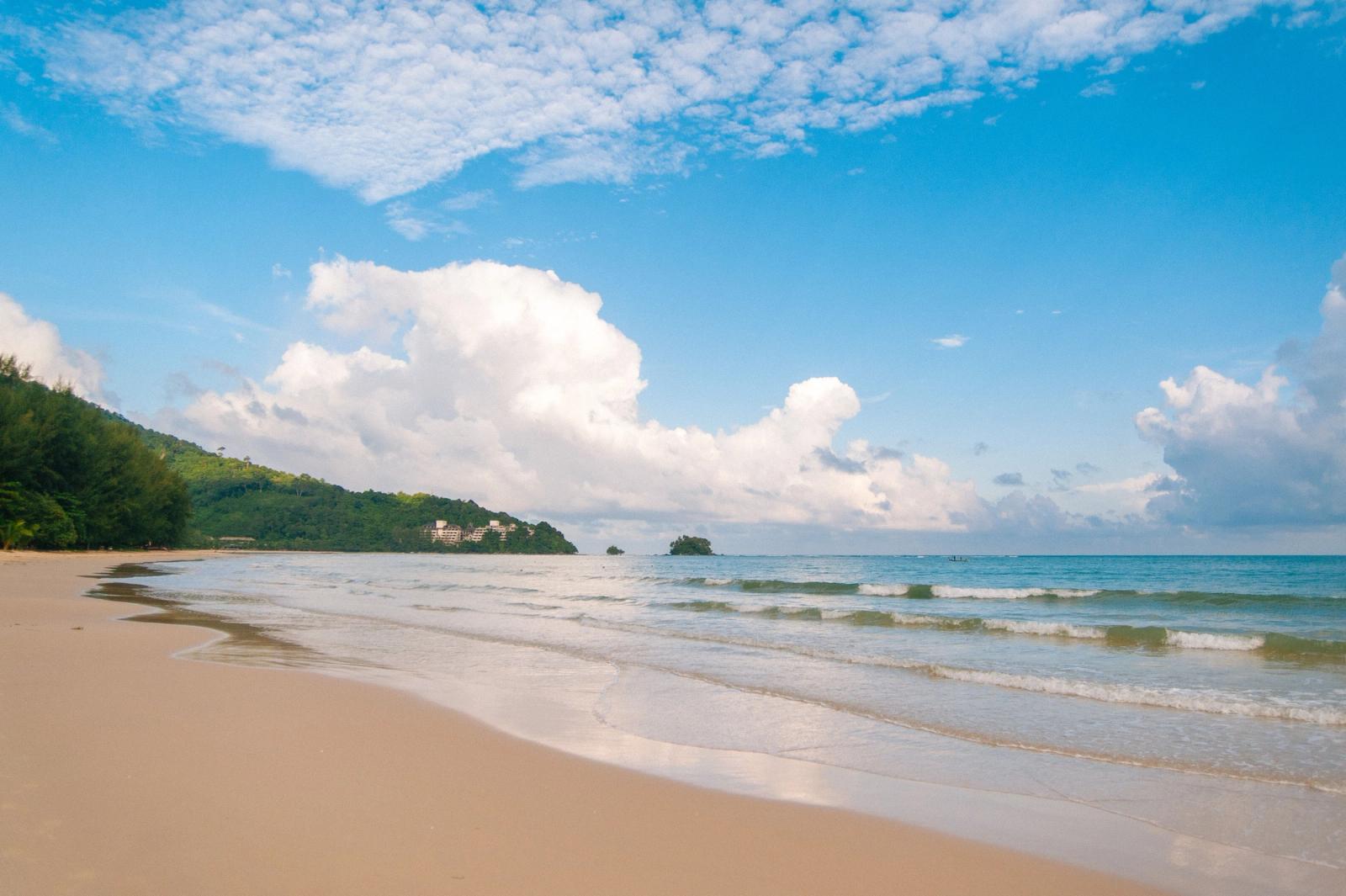 A serene beach view in Phuket, Thailand with gentle waves and a clear blue sky