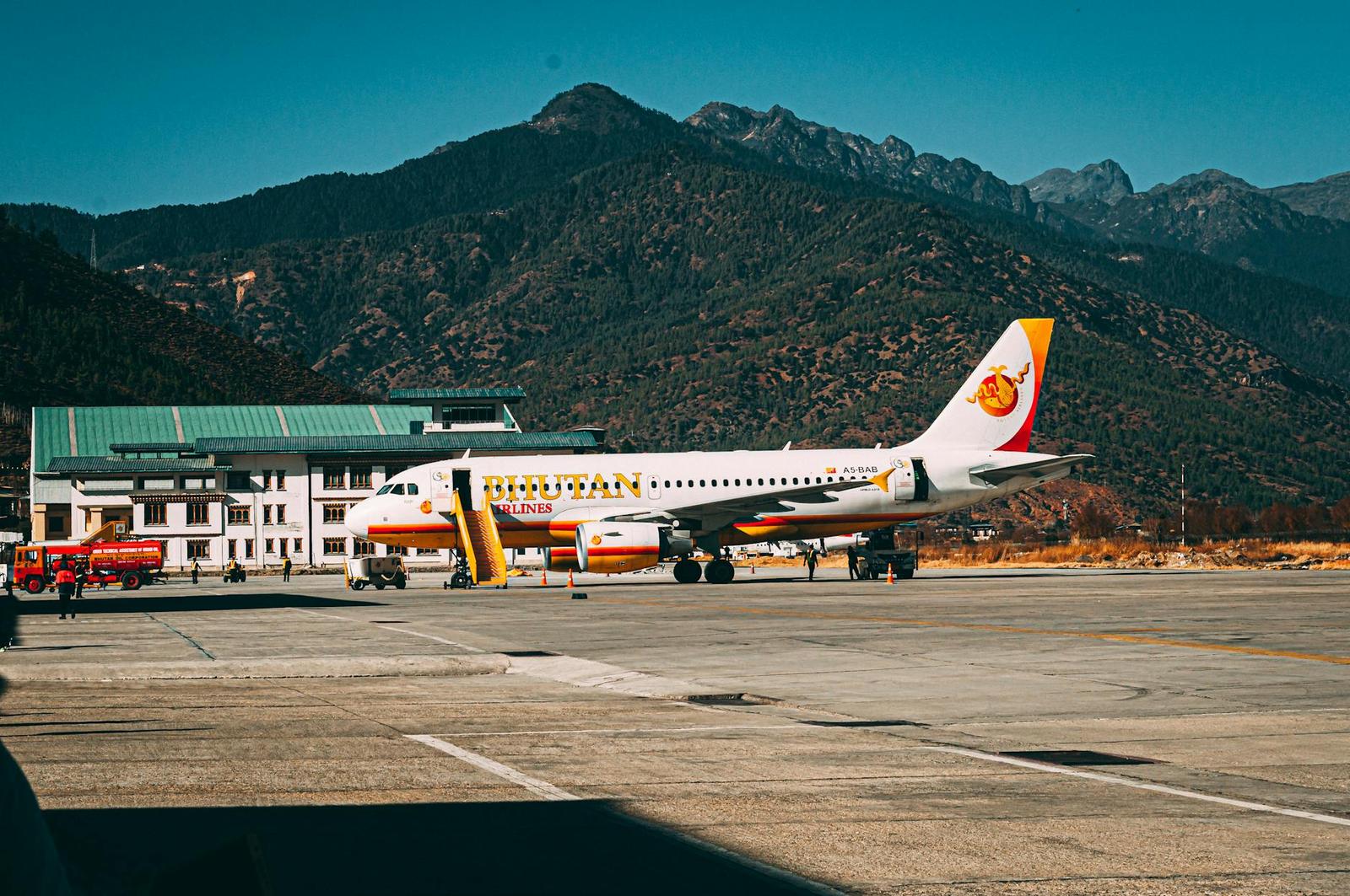 A Bhutan Airlines aircraft parked at Paro Airport with scenic mountain backdrop