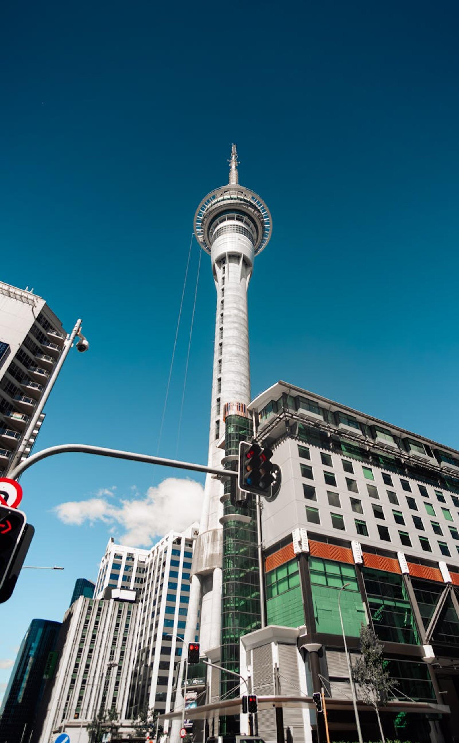 Tall observation tower rising above city buildings under a clear blue sky