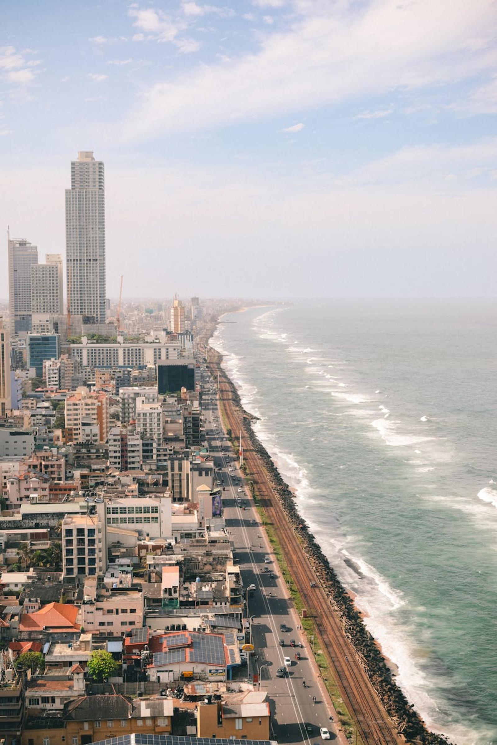 Aerial view of a coastal city road running alongside crashing surf