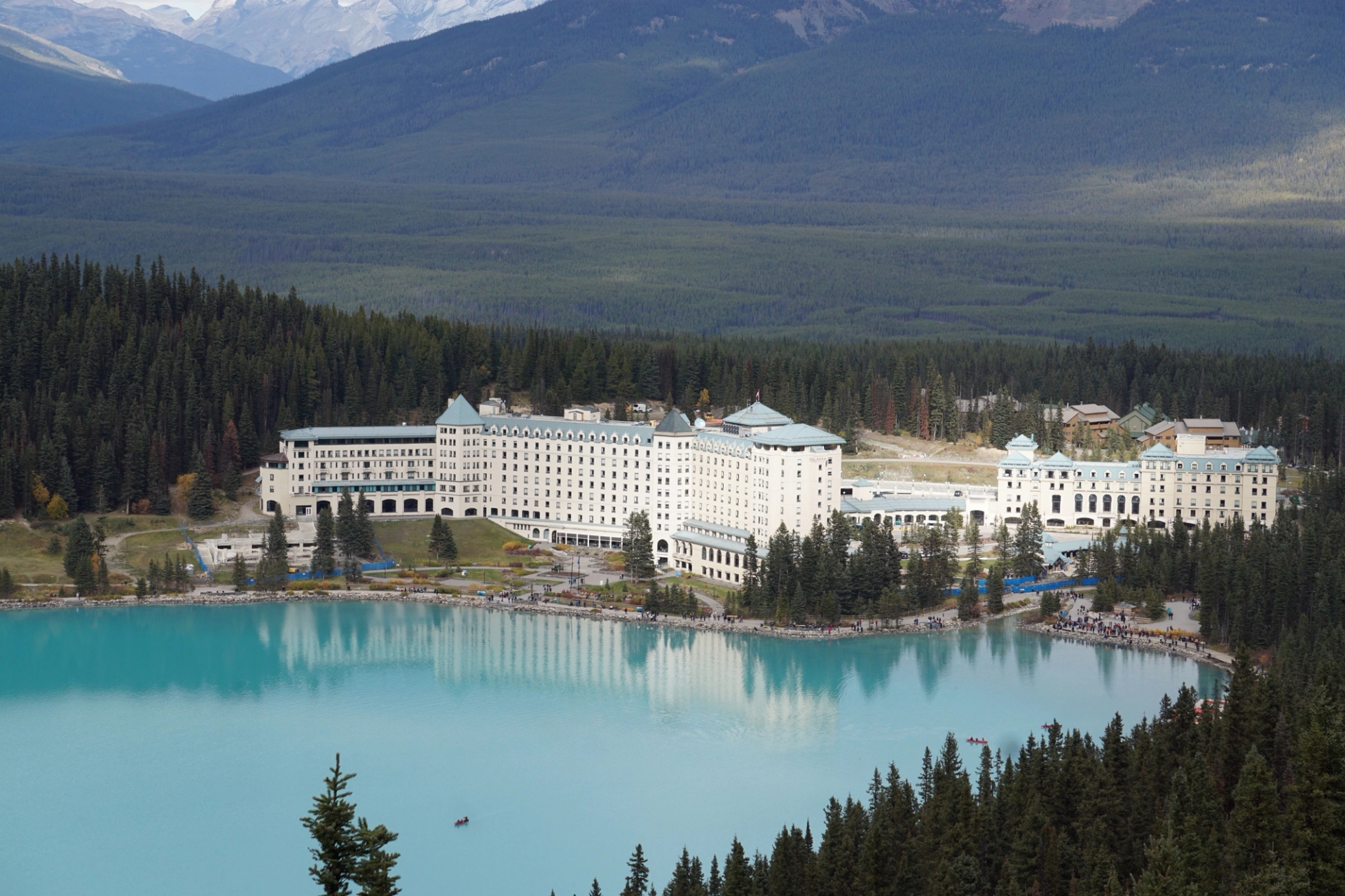 A stunning aerial view of Fairmont Chateau Lake Louise with turquoise waters and forested mountains in Canada