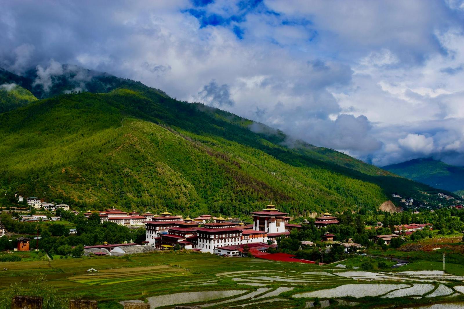 A large fortress-monastery complex spread across a green valley floor
