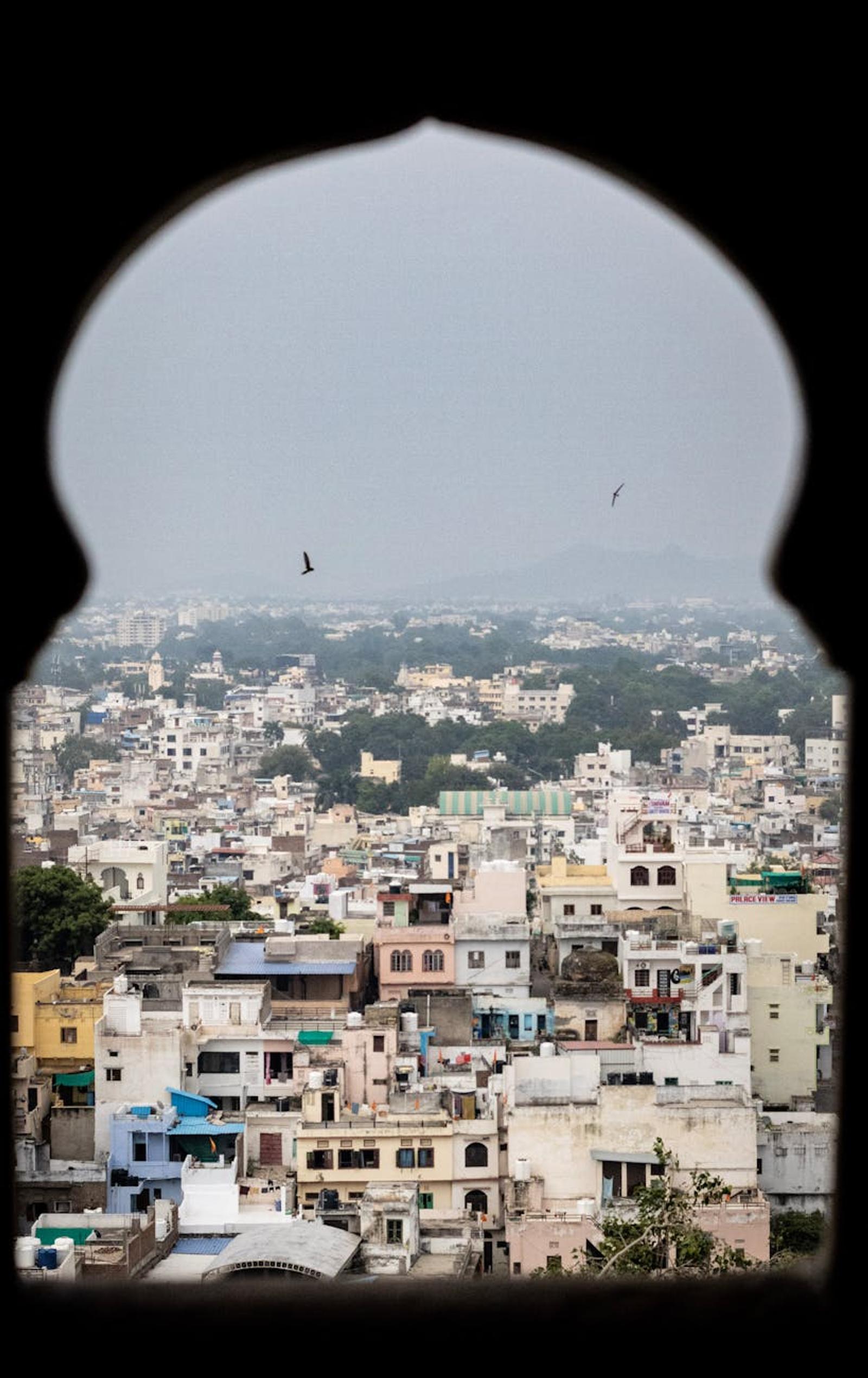 Explore the vibrant cityscape of Udaipur, Rajasthan, framed through a traditional arch
