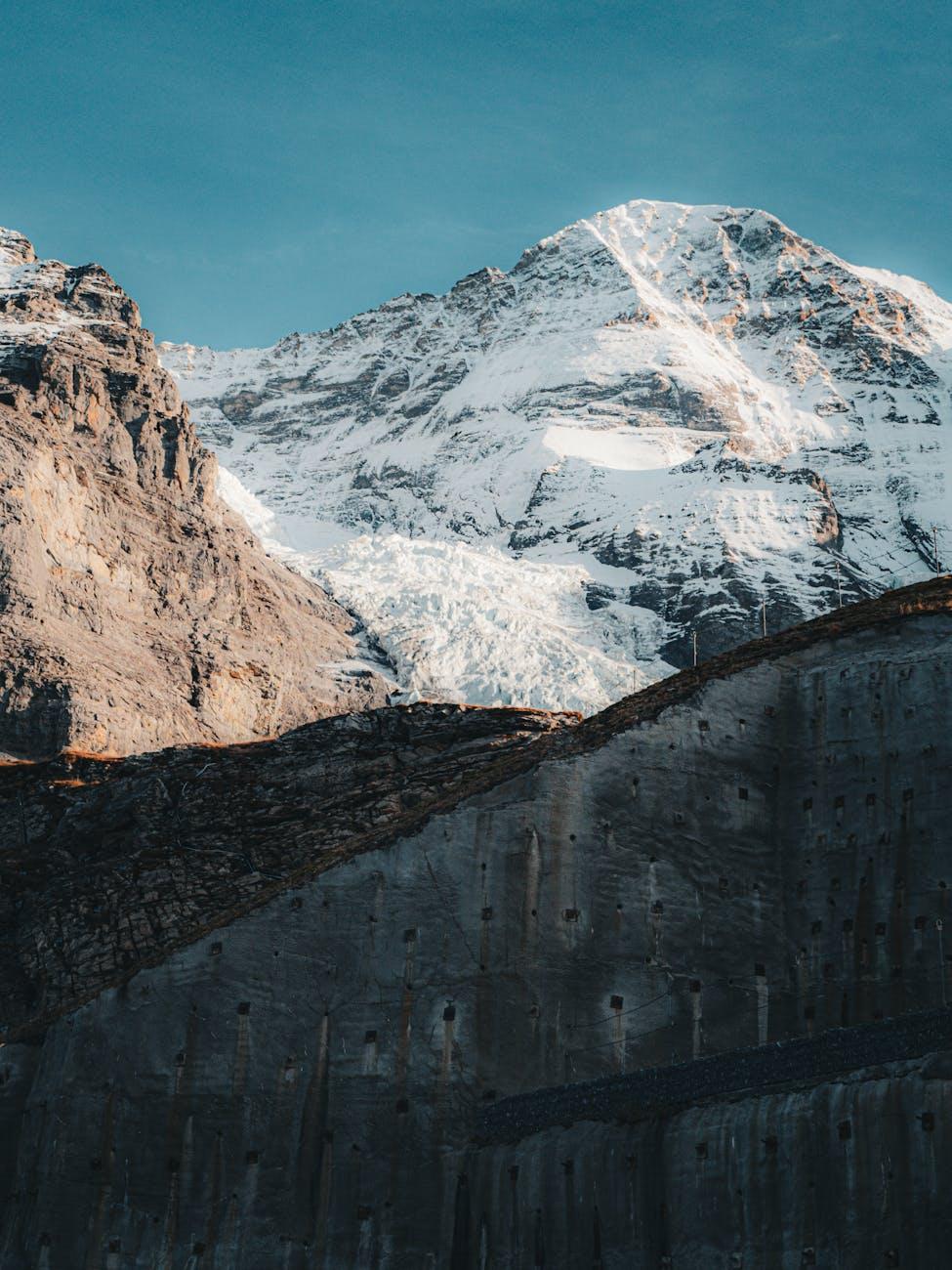 Snowy peak and glacier seen past a concrete rooftop terrace at dusk