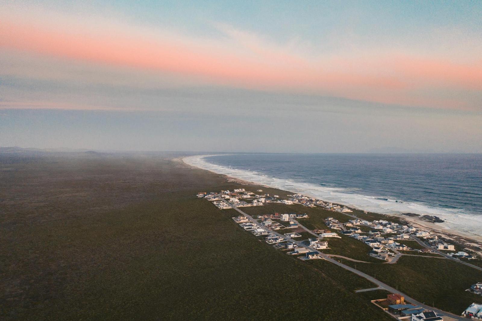 Aerial view of a small coastal settlement along a foggy shoreline at dusk