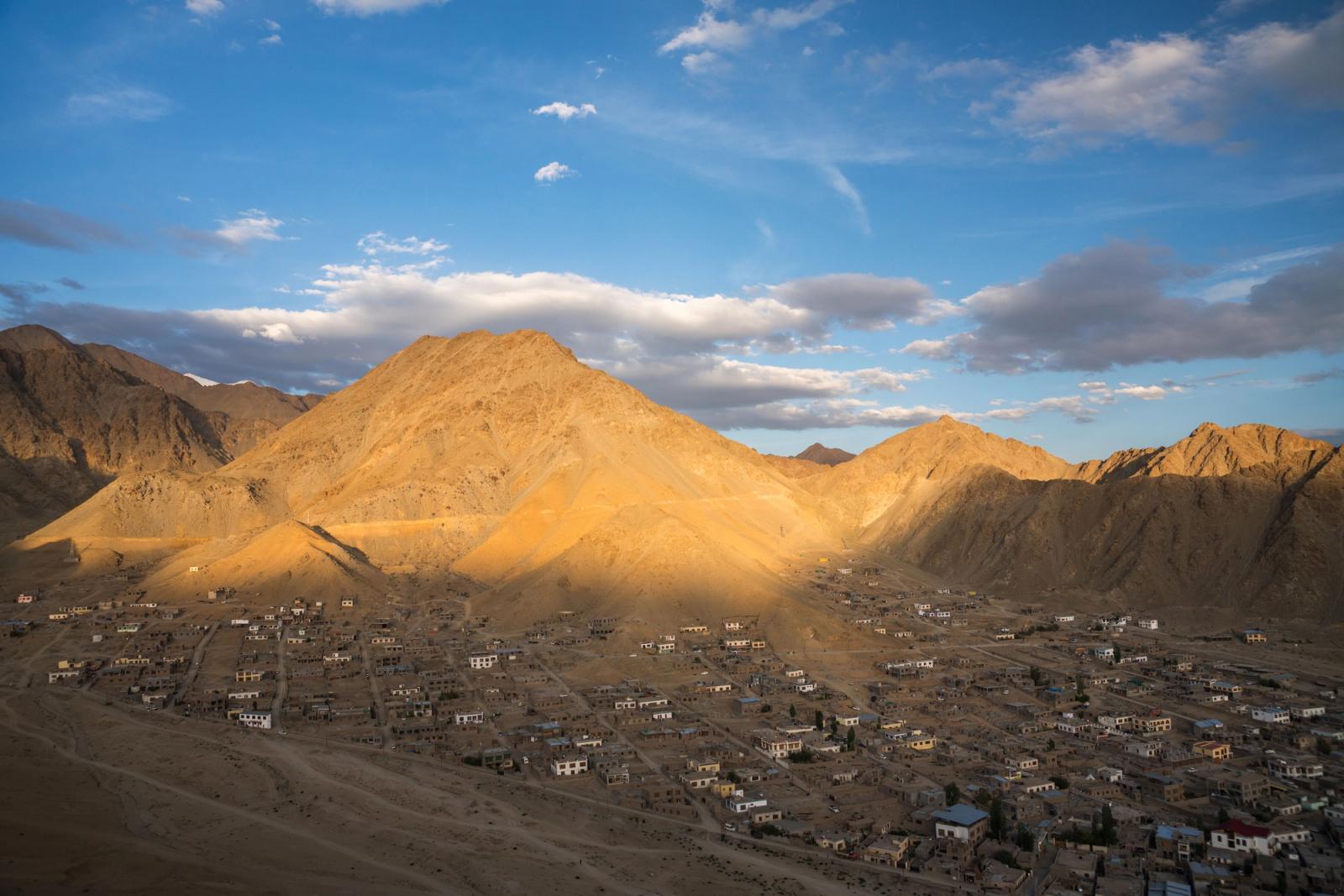 A mountain town lit by warm evening light against tall peaks