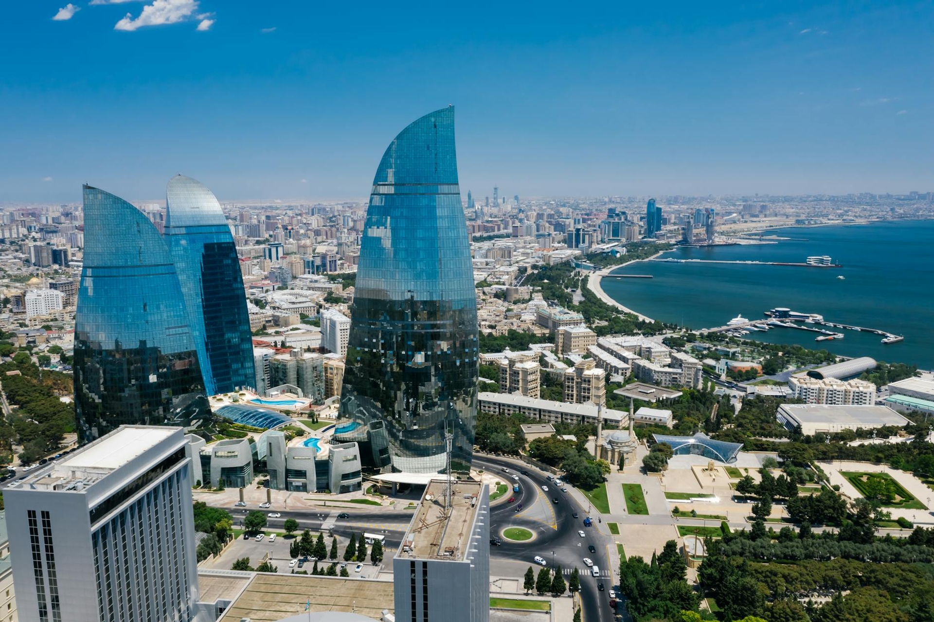 Aerial view of curved glass skyscrapers rising above a coastal city