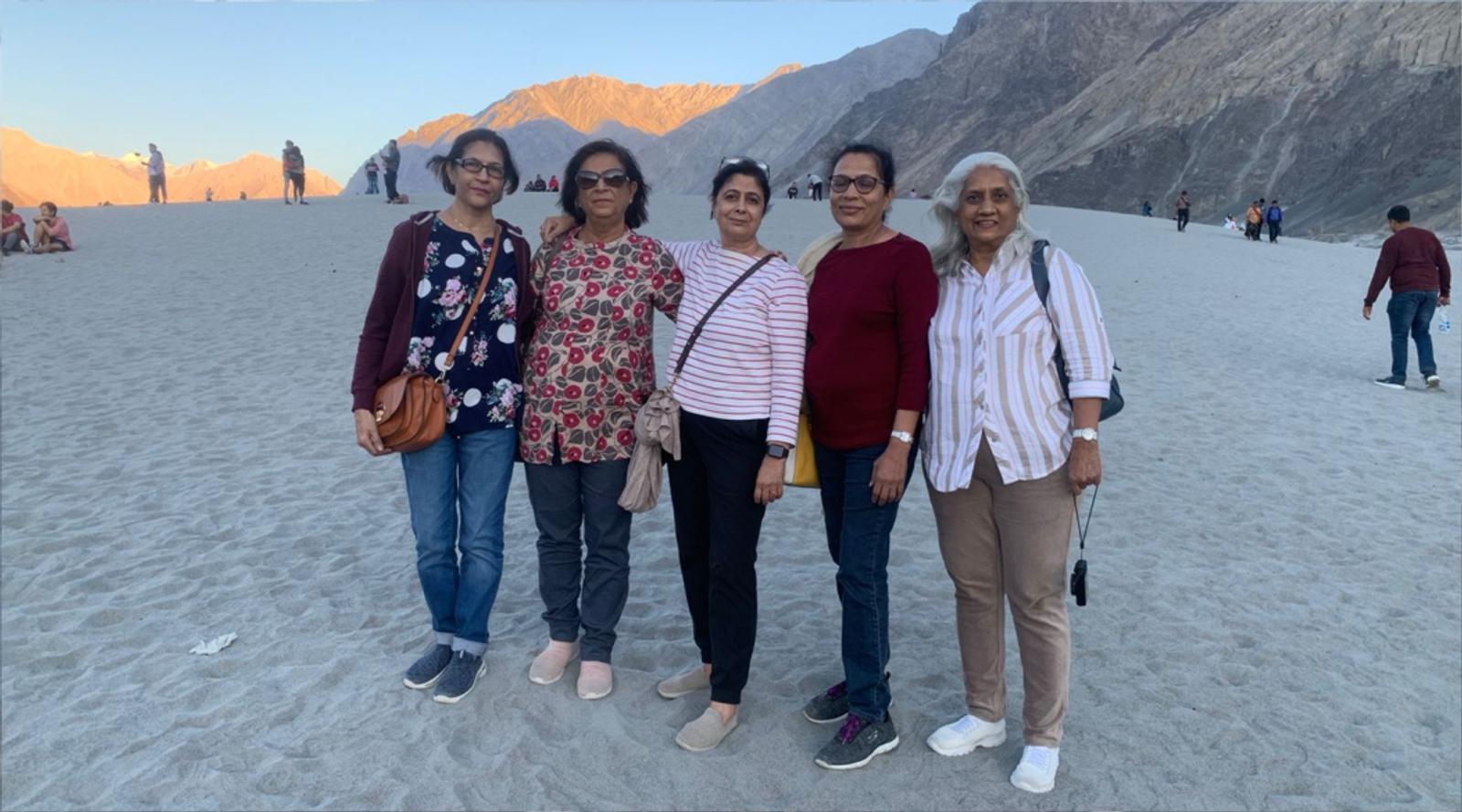 Five women posing together in a scenic desert landscape.