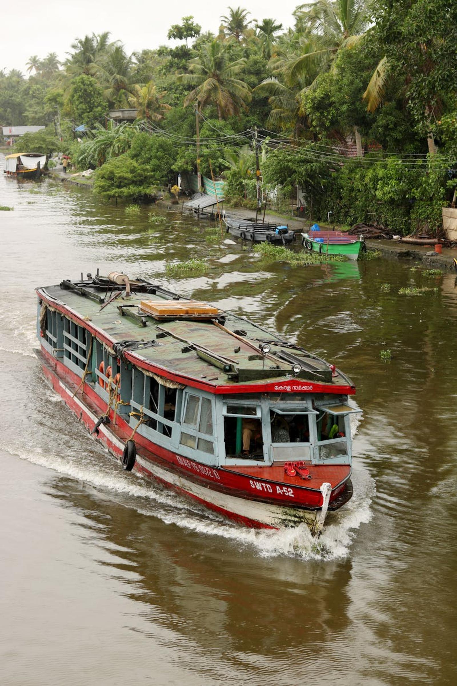 A vibrant ferry boat traversing the serene backwaters of Alappuzha, Kerala amidst lush greenery