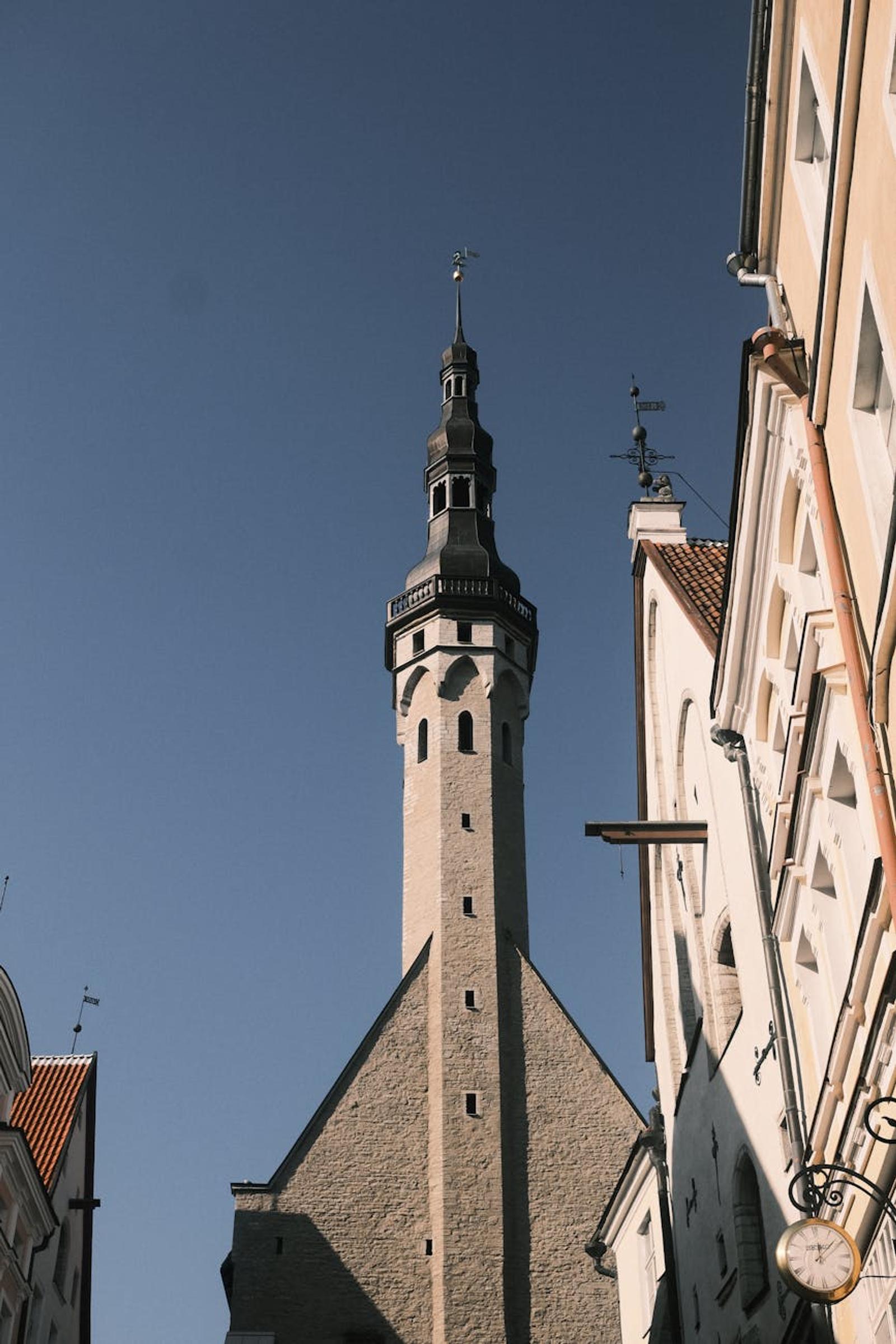 Stone church spire rising above a narrow lane of old buildings