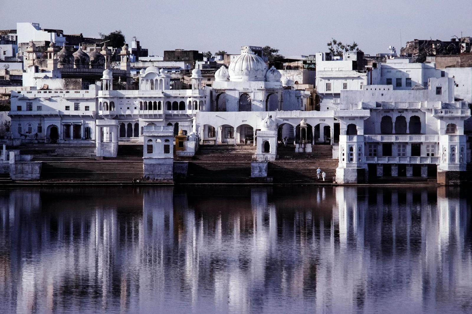 Symmetrical white domed palace complex reflected in a calm lake