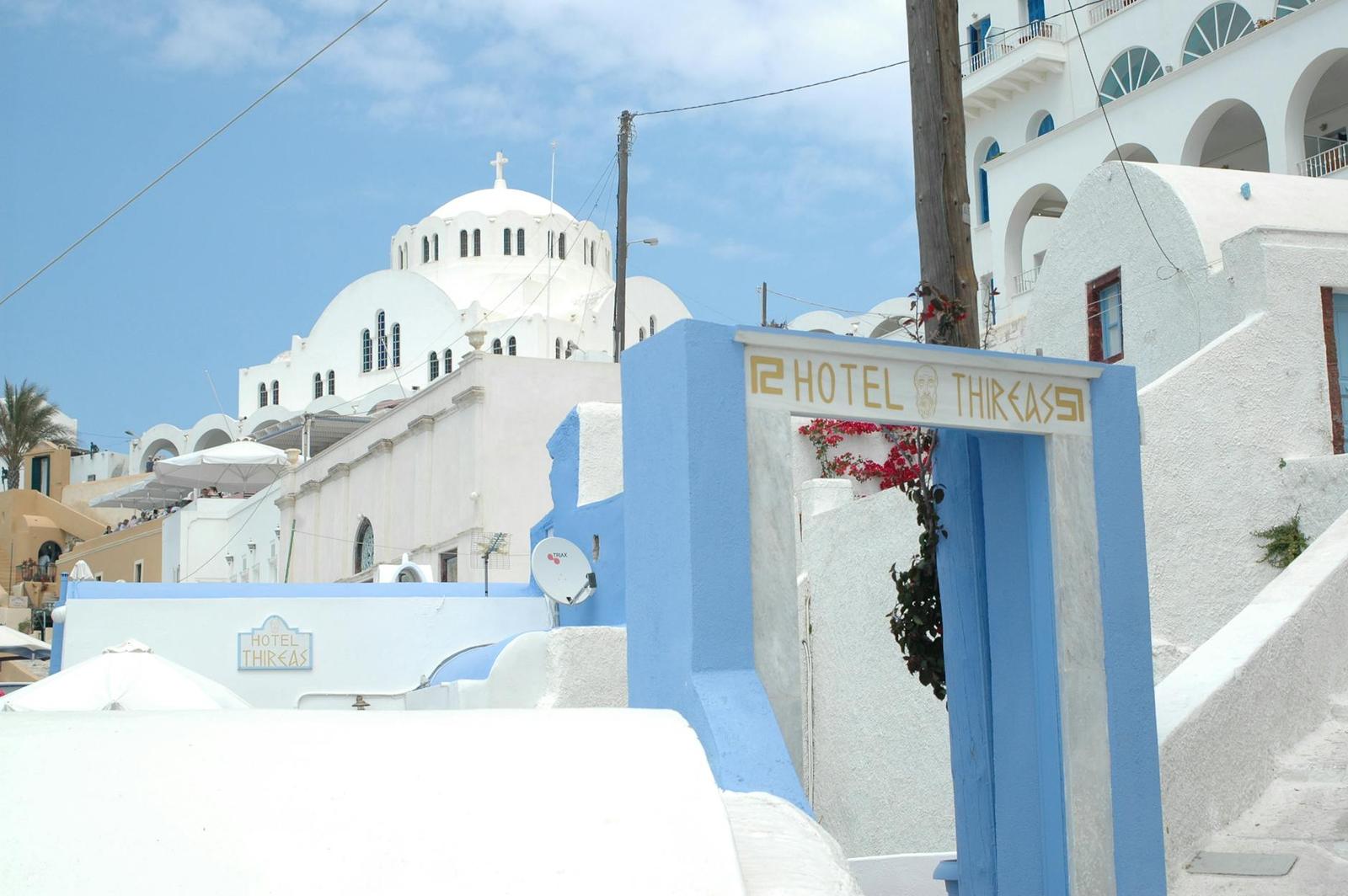 A blue-domed church rising behind a whitewashed hotel entrance sign