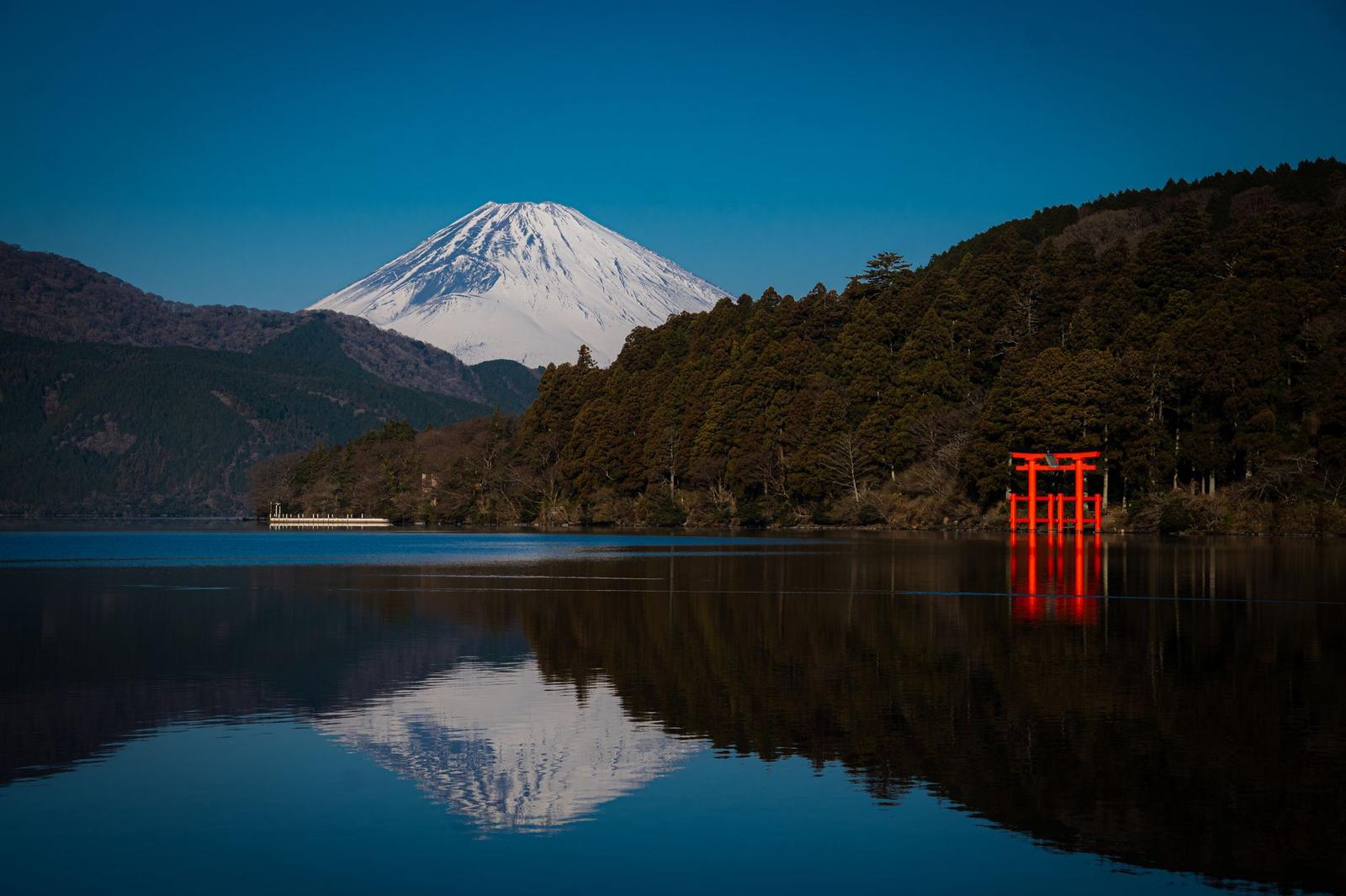 Stunning view of Mount Fuji and a red torii gate reflecting in Lake Ashi, Hakone, Japan