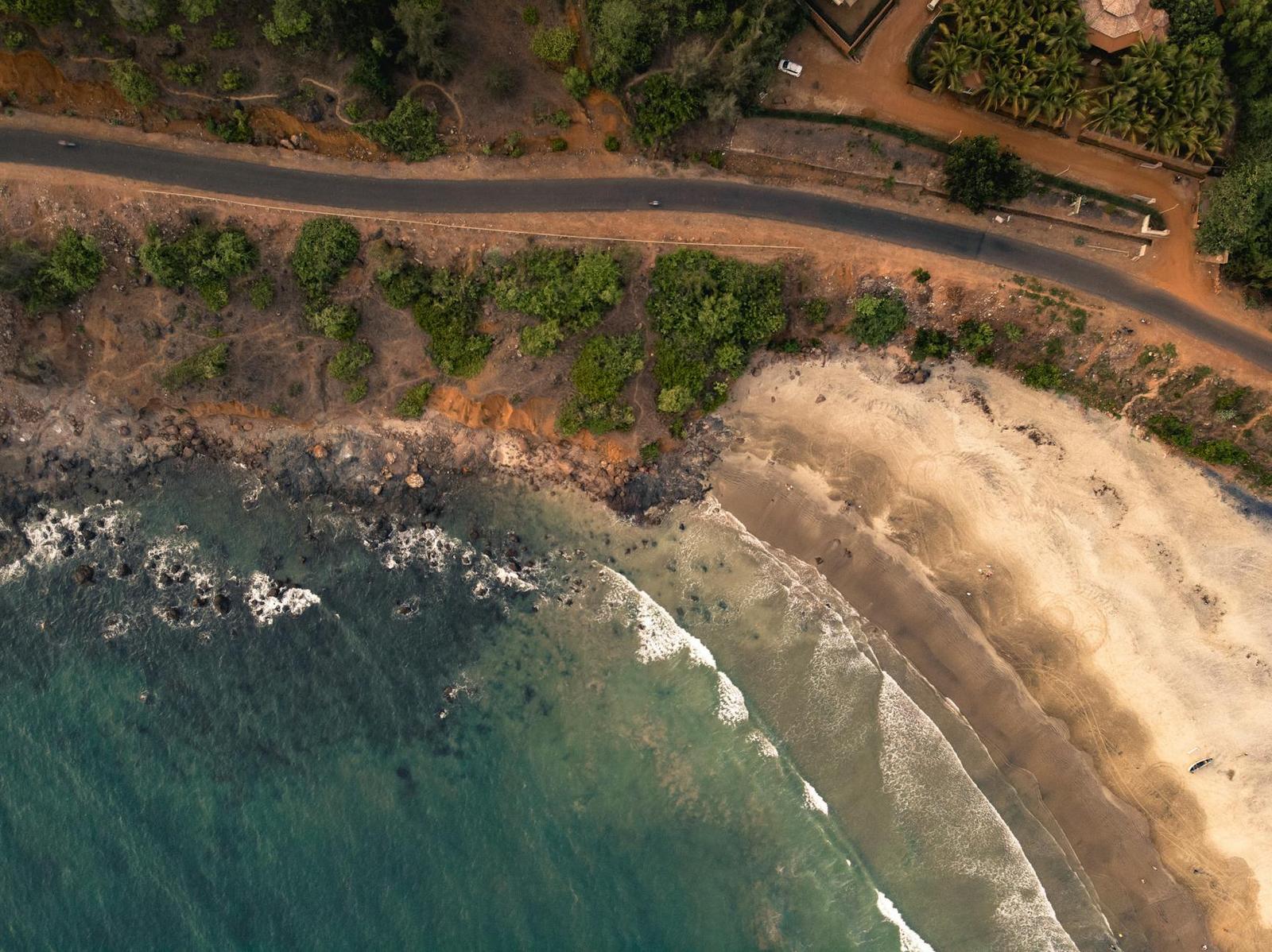 An aerial view of a coastal road running along cliffs above a beach