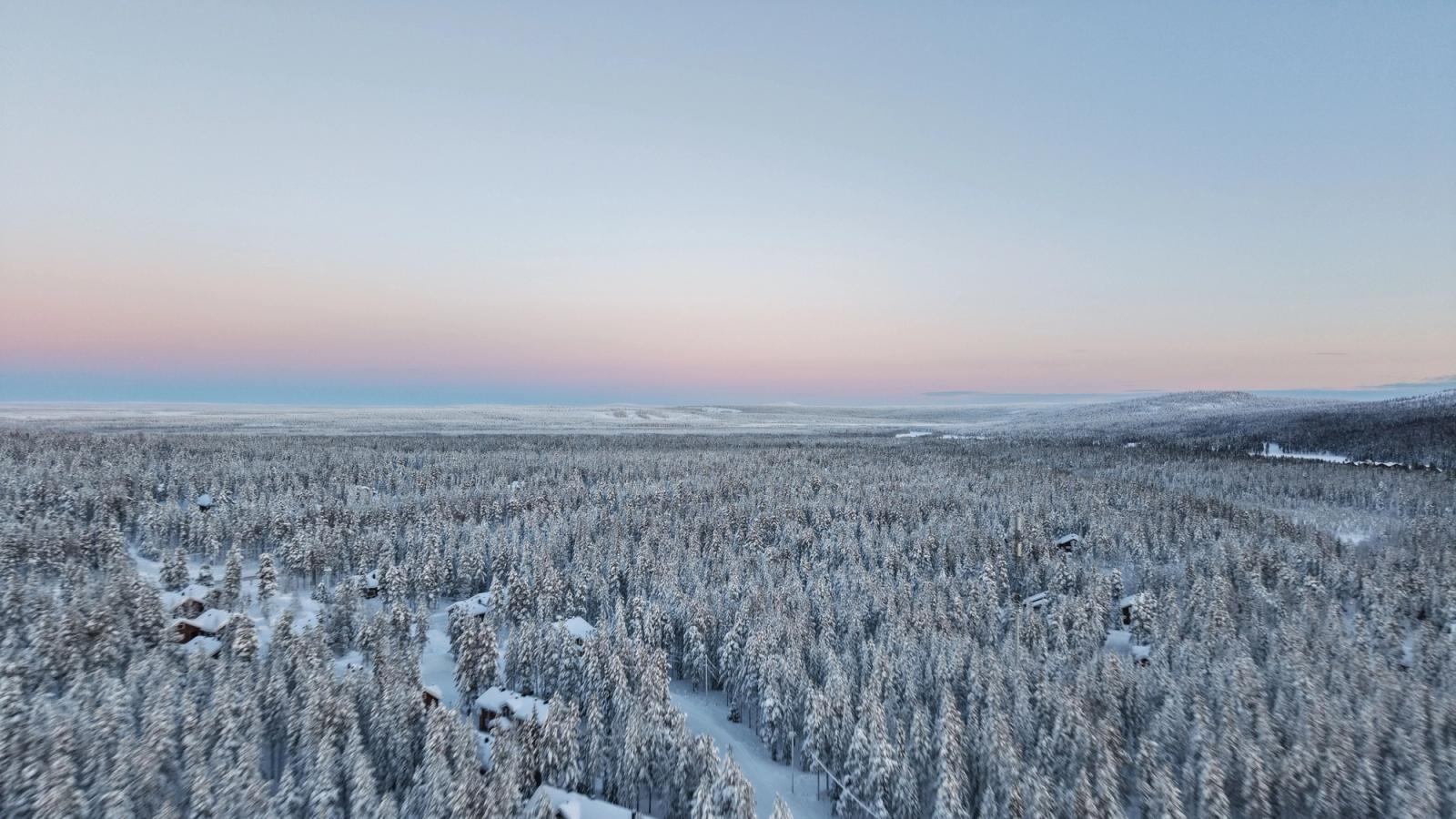 A breathtaking aerial view of snowy forests at dawn in Finland, showcasing winter's serene beauty